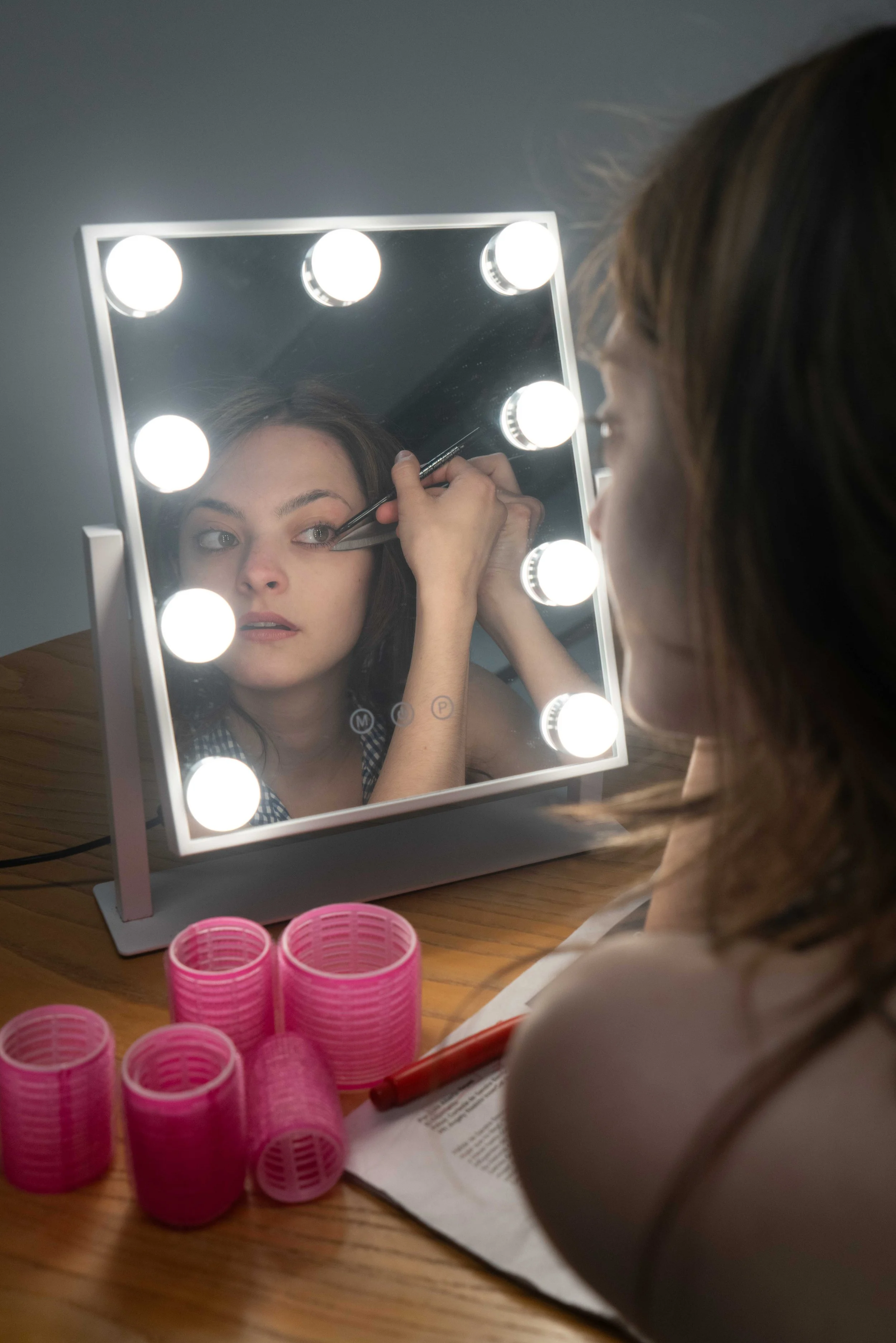 Image of actor Selina Piros putting on eyeliner in a mirror