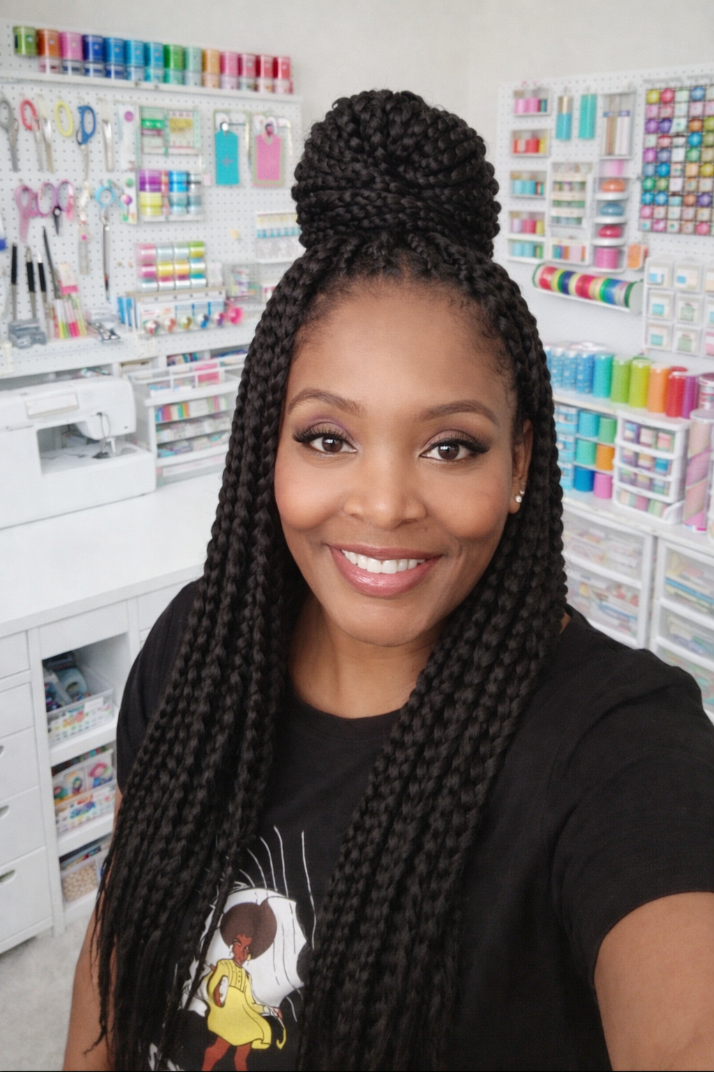 A woman with long braided hair taking a selfie in a craft store filled with colorful supplies