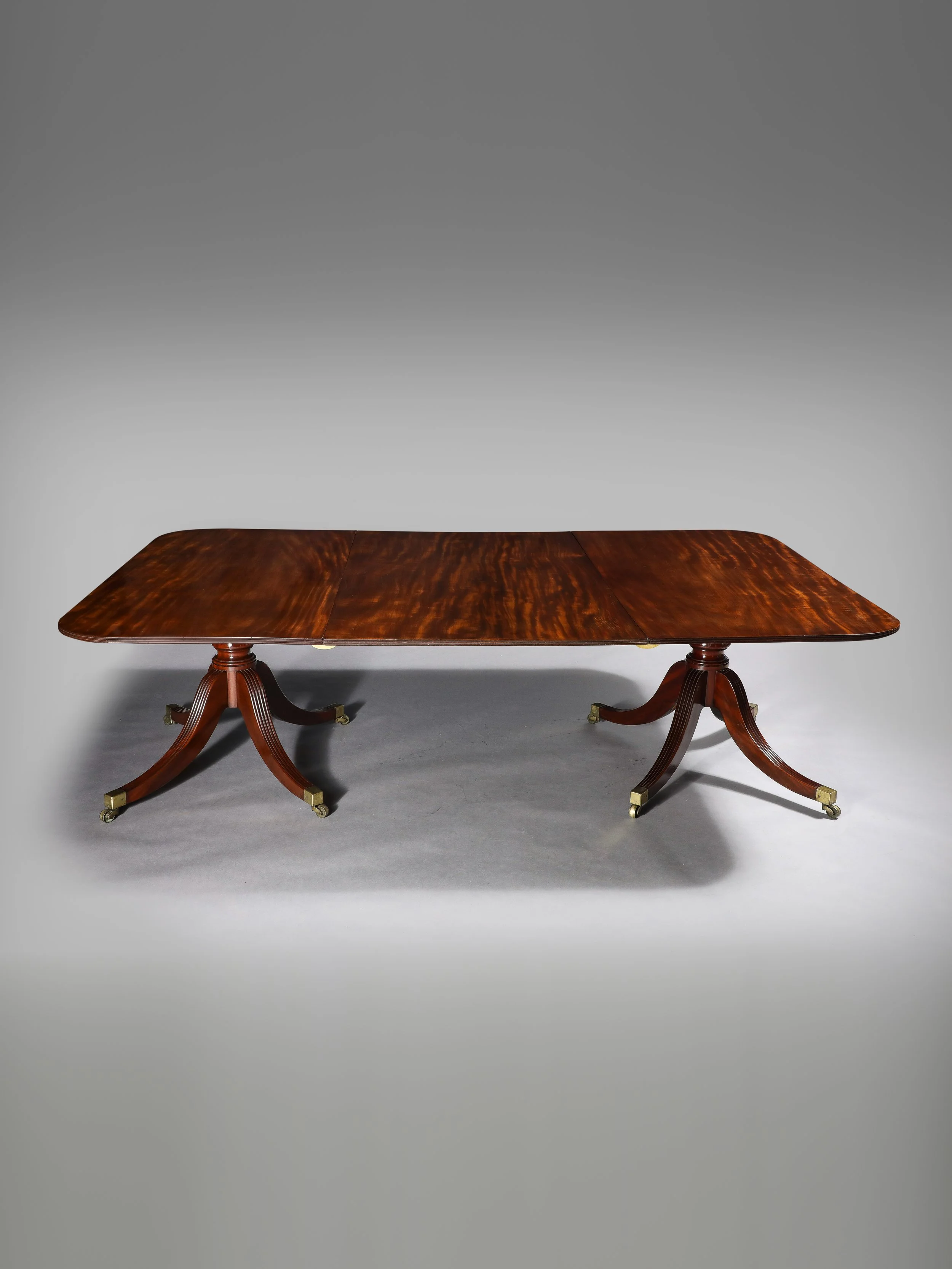 A George III Regency Figured Mahogany Double Pedestal Extension Dining Table · Early 19th century