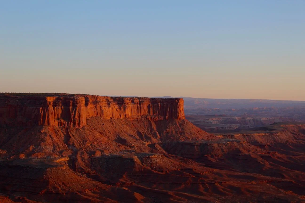 Sunset over the red rock formations of a canyon in the desert.