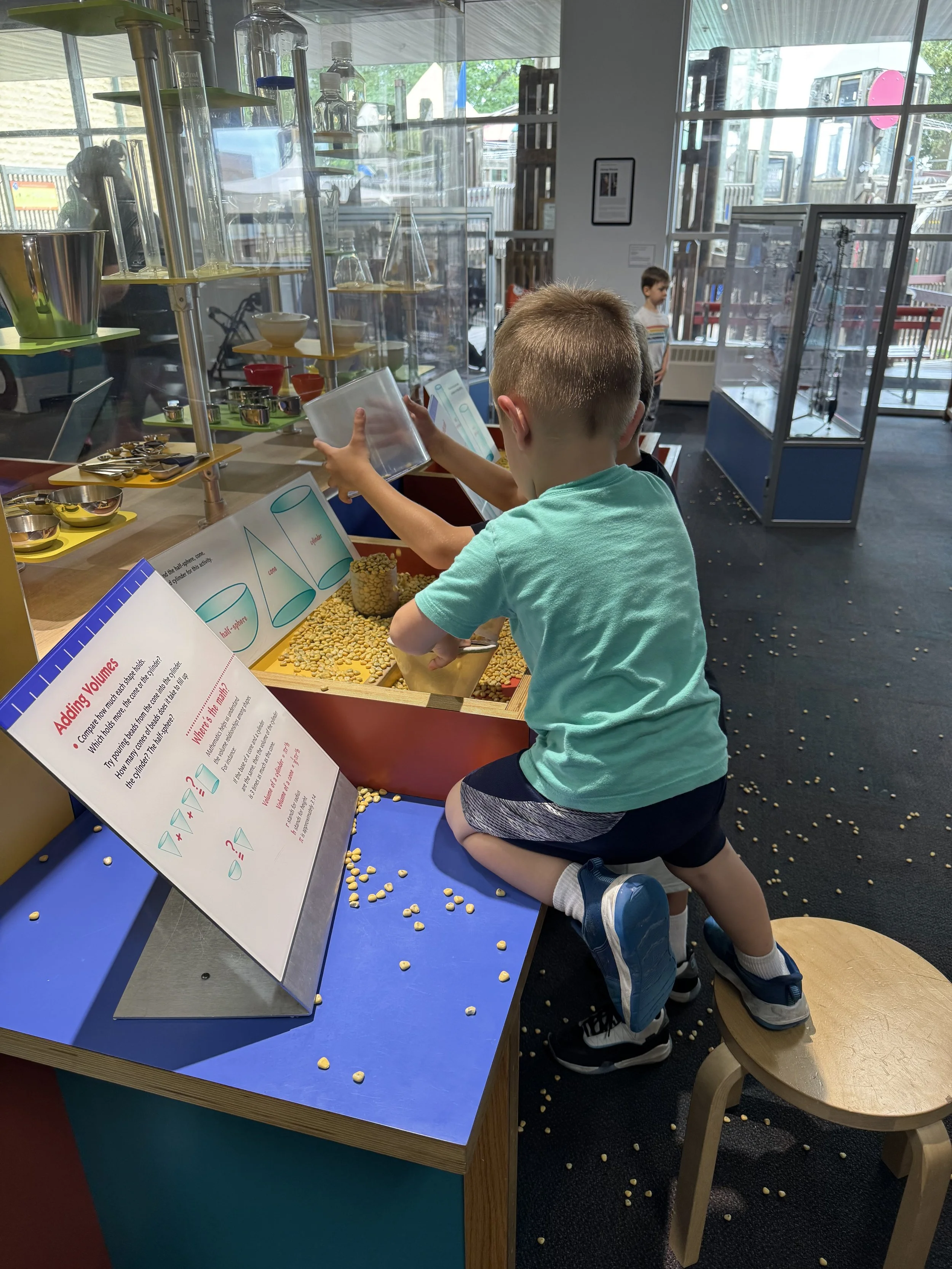 A small male child engaging with an exhibit about measuring volume at a children's museum.