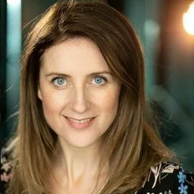 Headshot of Liz Flint with light brown hair and blue eyes, smiling at the camera.