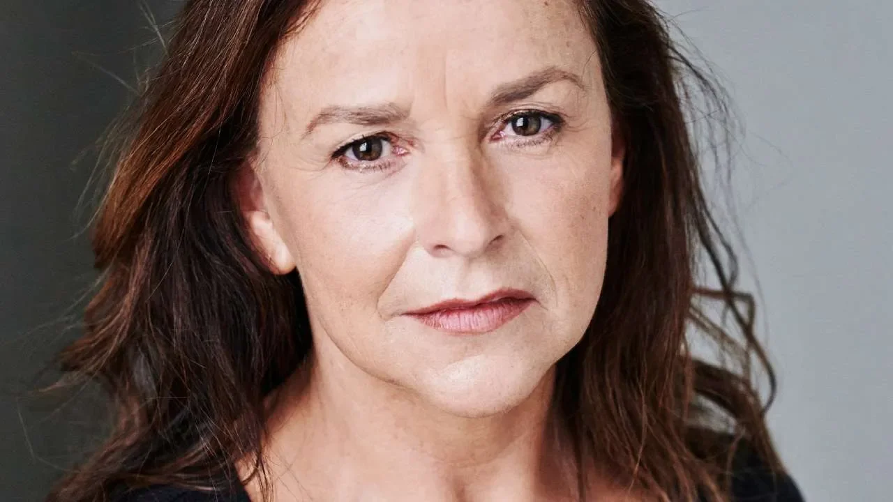 Close-up portrait of Sally-Ann Triplett, actress with auburn hair and fair skin, looking directly at the camera with a serious expression.