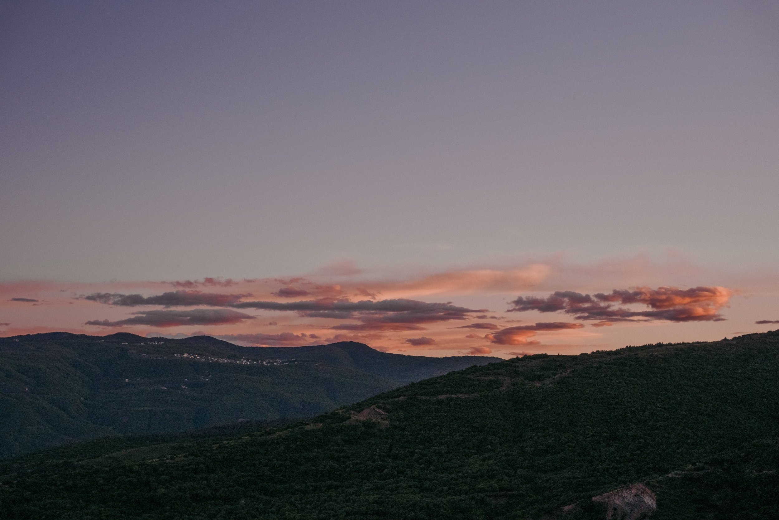 Napo Garden, the home of Camp Americana  with its landscape view of rolling green hills under a colorful sky with pink and orange clouds at sunset