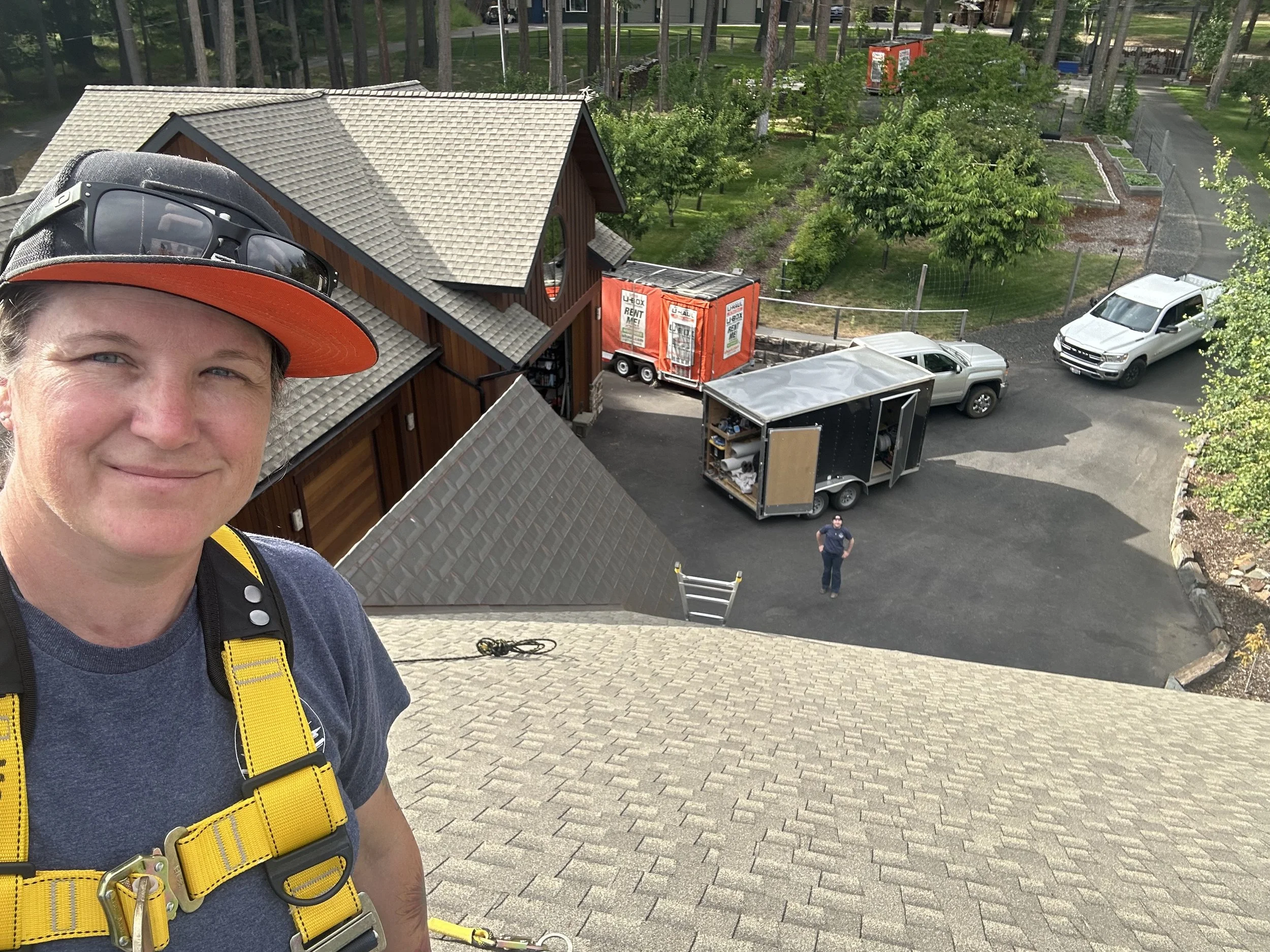 Electricians installing solar panels on roof while crew member works on ground in North Idaho