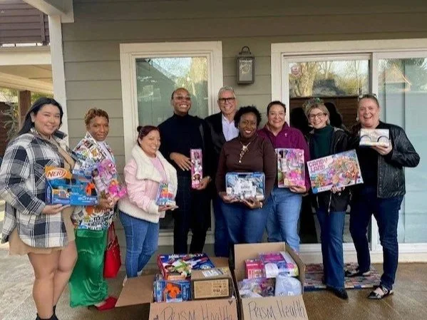 PHNTX staff and advocates holding toys and gifts from a holiday toy drive.