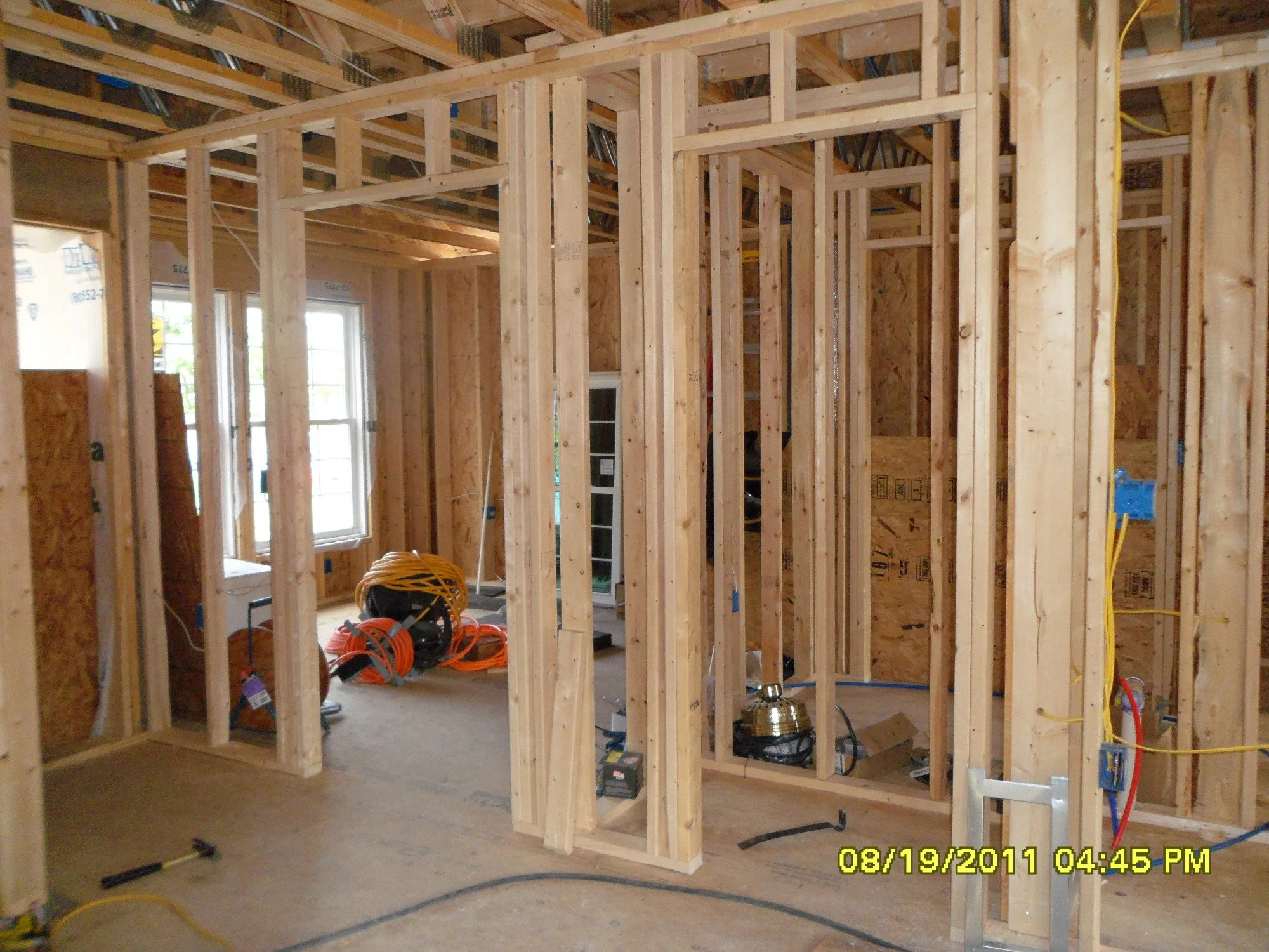 Interior of a house under construction with exposed wooden framing and electrical wiring.