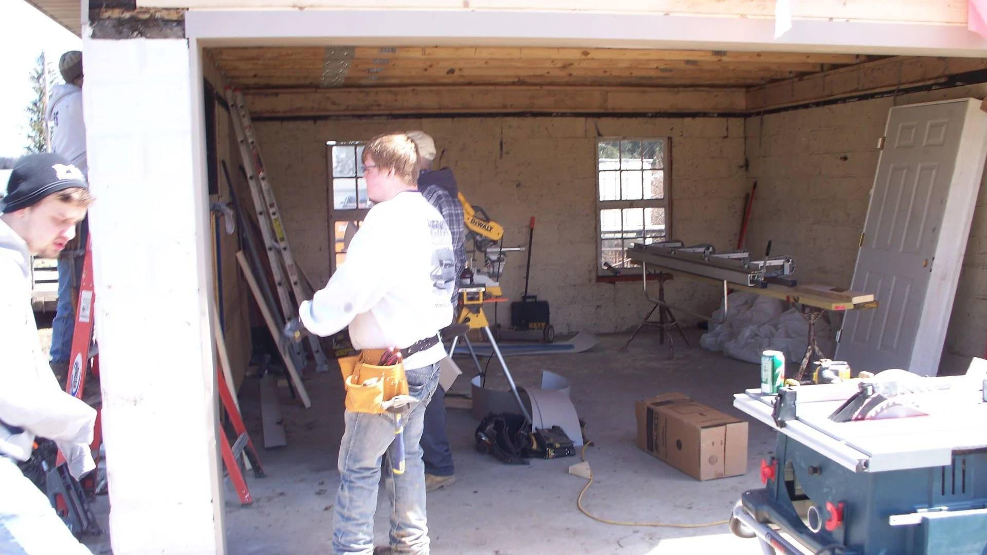 Construction workers inside a house under renovation with tools, ladders, and construction materials.