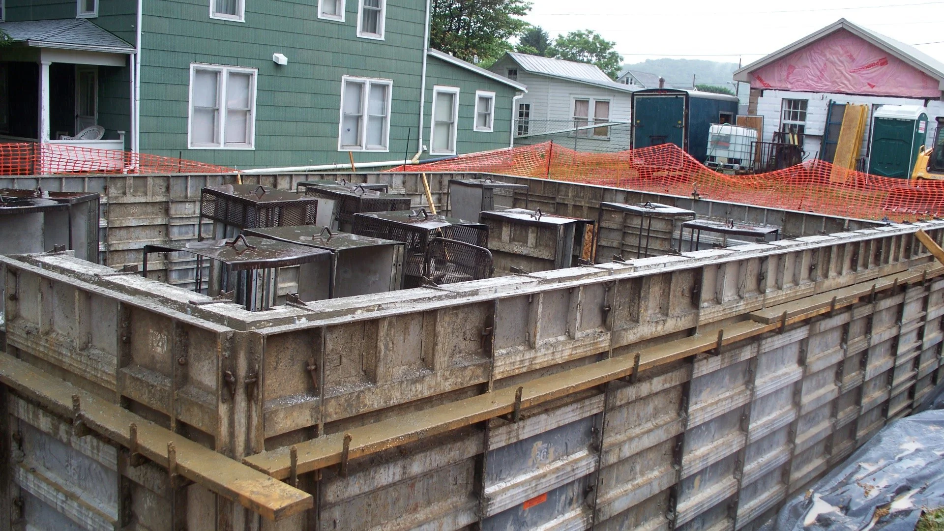 Construction site with metal framework and orange safety barriers in a residential area