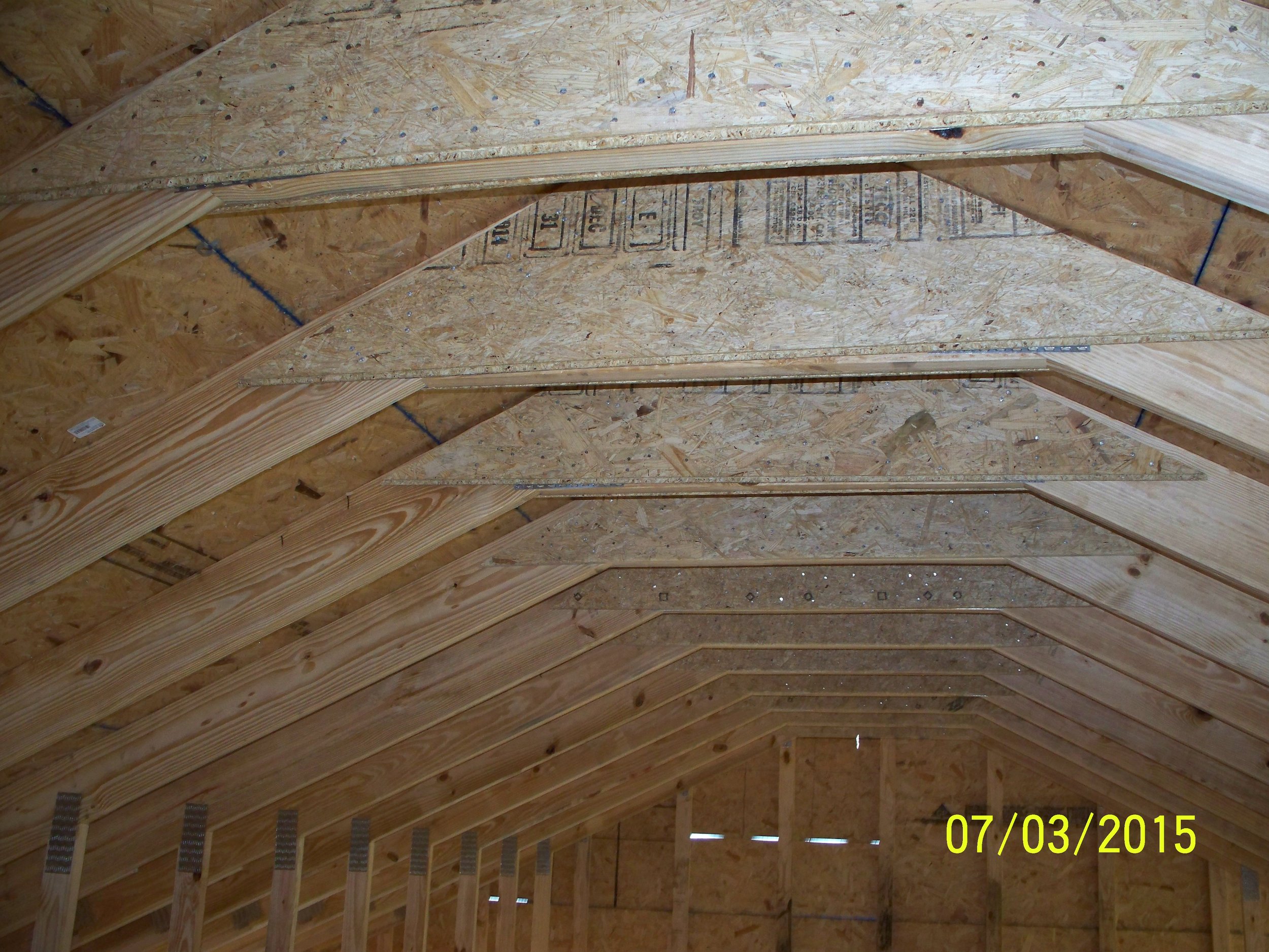 Interior view of a building under construction with exposed wooden framing and roof trusses
