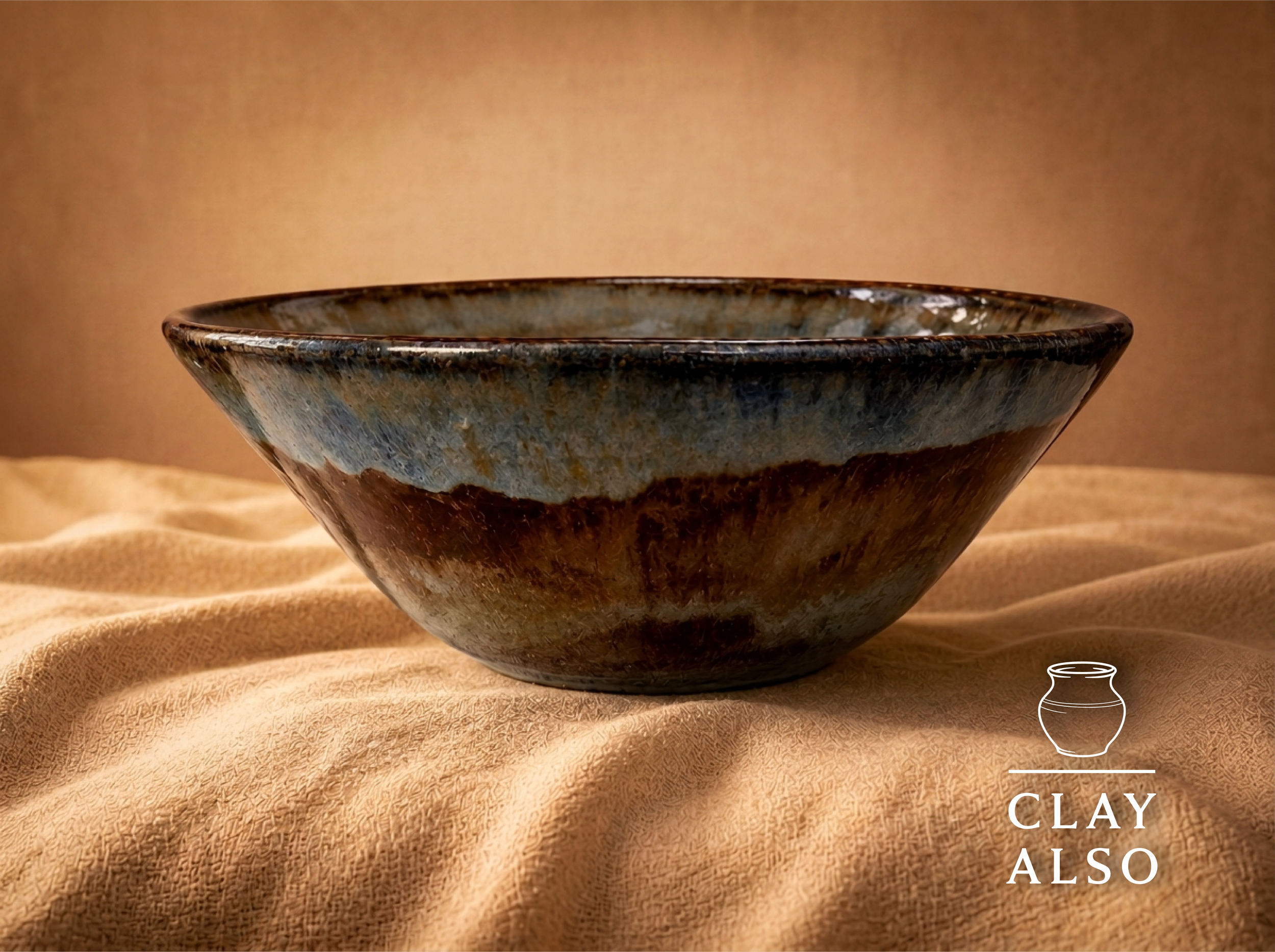 A ceramic bowl with a textured, multicolored glaze sitting on a textured beige fabric surface.