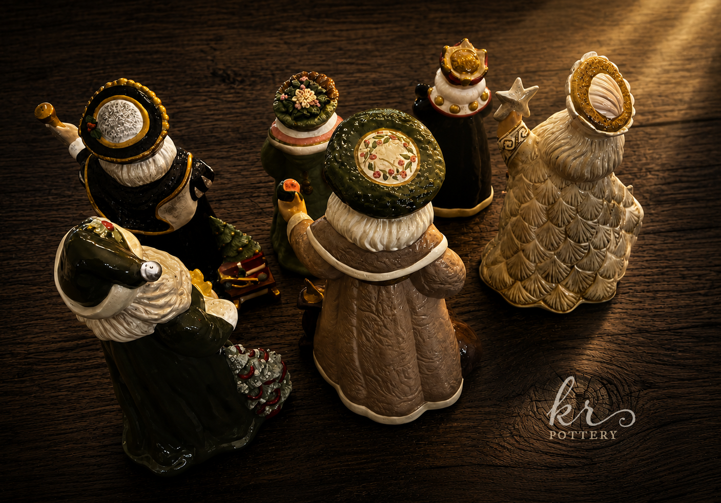 Collection of ceramic Christmas figurines depicting Santa Claus and a sheep, displayed on a dark wooden surface.