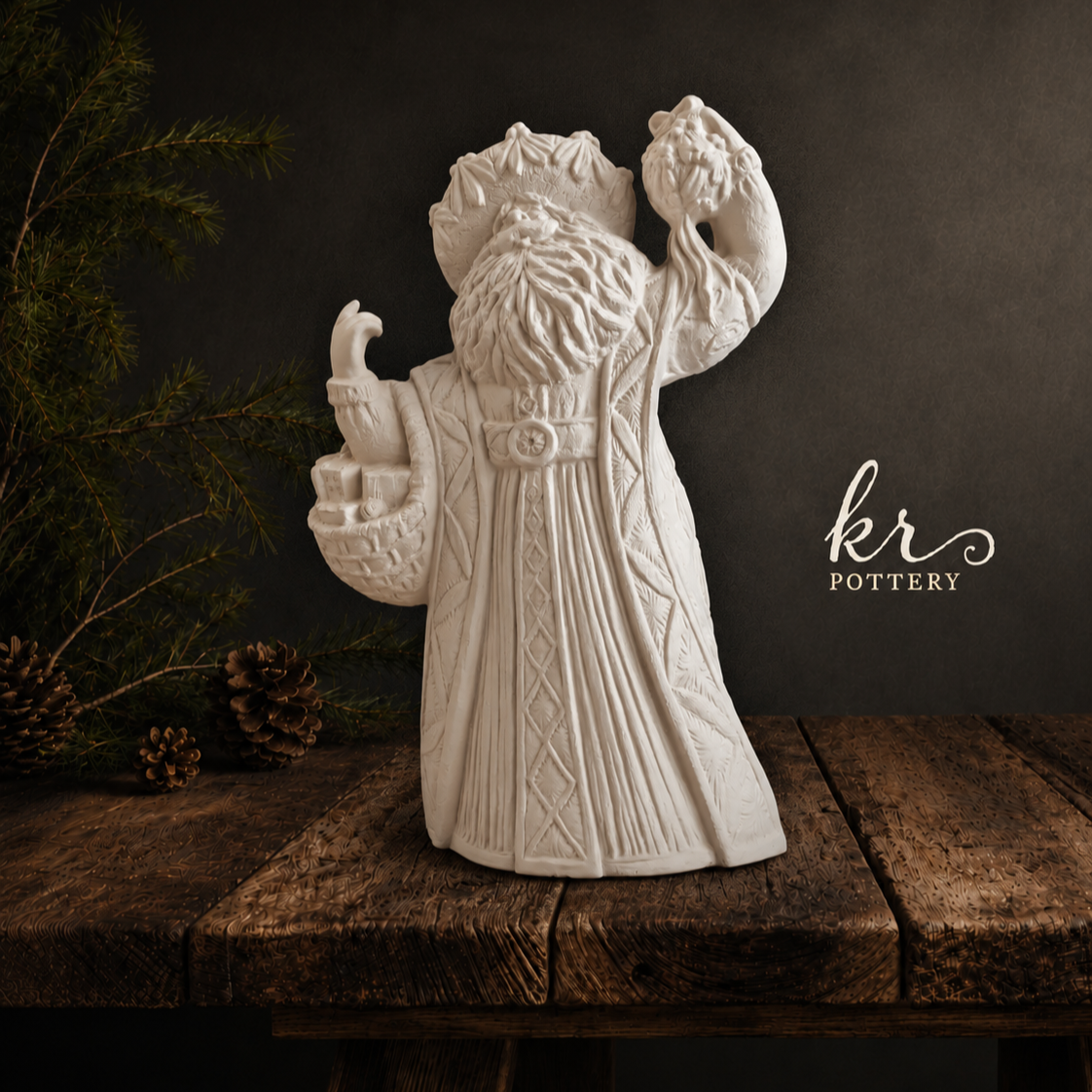 Gare Santa right out of the kiln standing on a wooden surface, with pine branches and pinecones, and text that reads 'kr Pottery' in the background.
