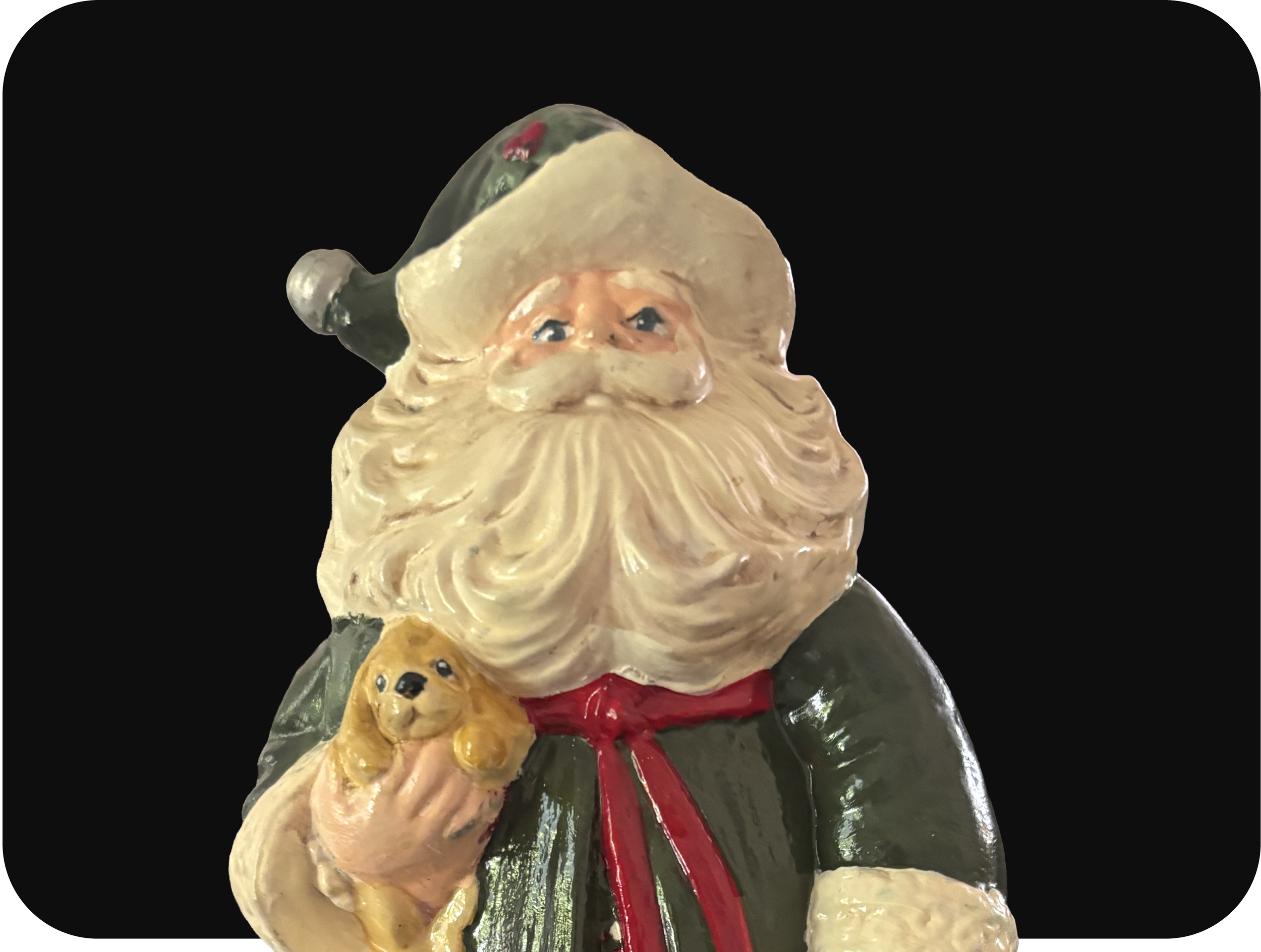A vintage ceramic Santa Claus figurine with a white beard, holding a small teddy bear, dressed in a green coat and red tie, set against a black background.