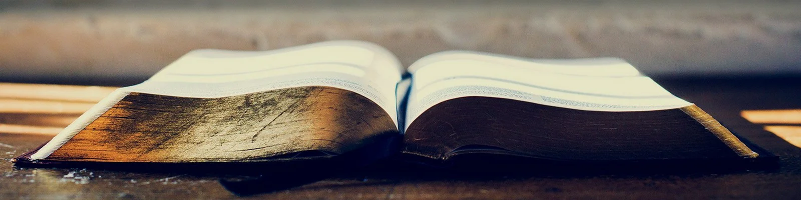 Open book with visible text on pages, placed on a wooden surface