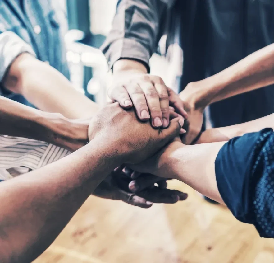 Multiple hands of diverse people stacked together in a gesture of unity and teamwork.