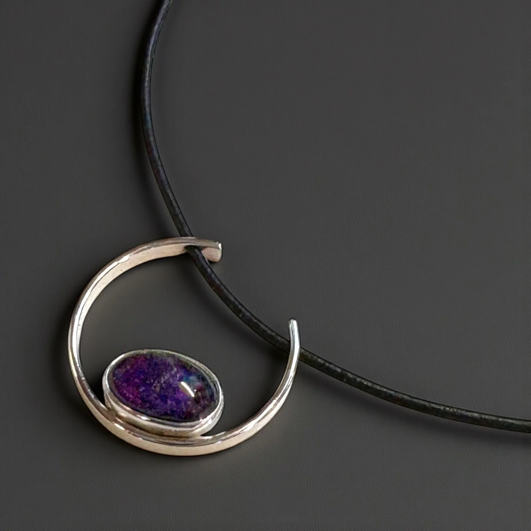 Oval amethyst in a sterling silver pendant with a sculptural silver arc.