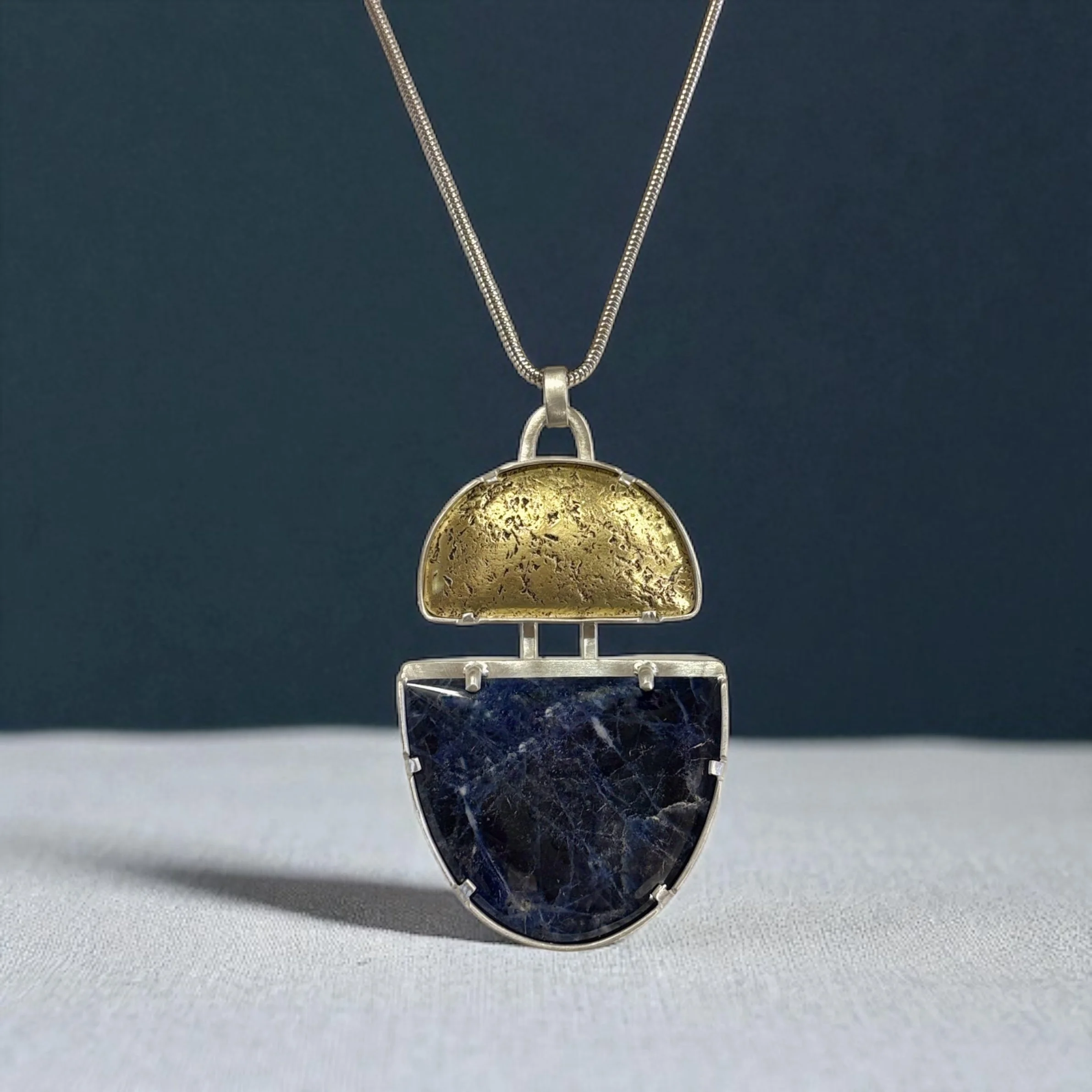 Sodalite set in sterling silver with a textured brass accent.