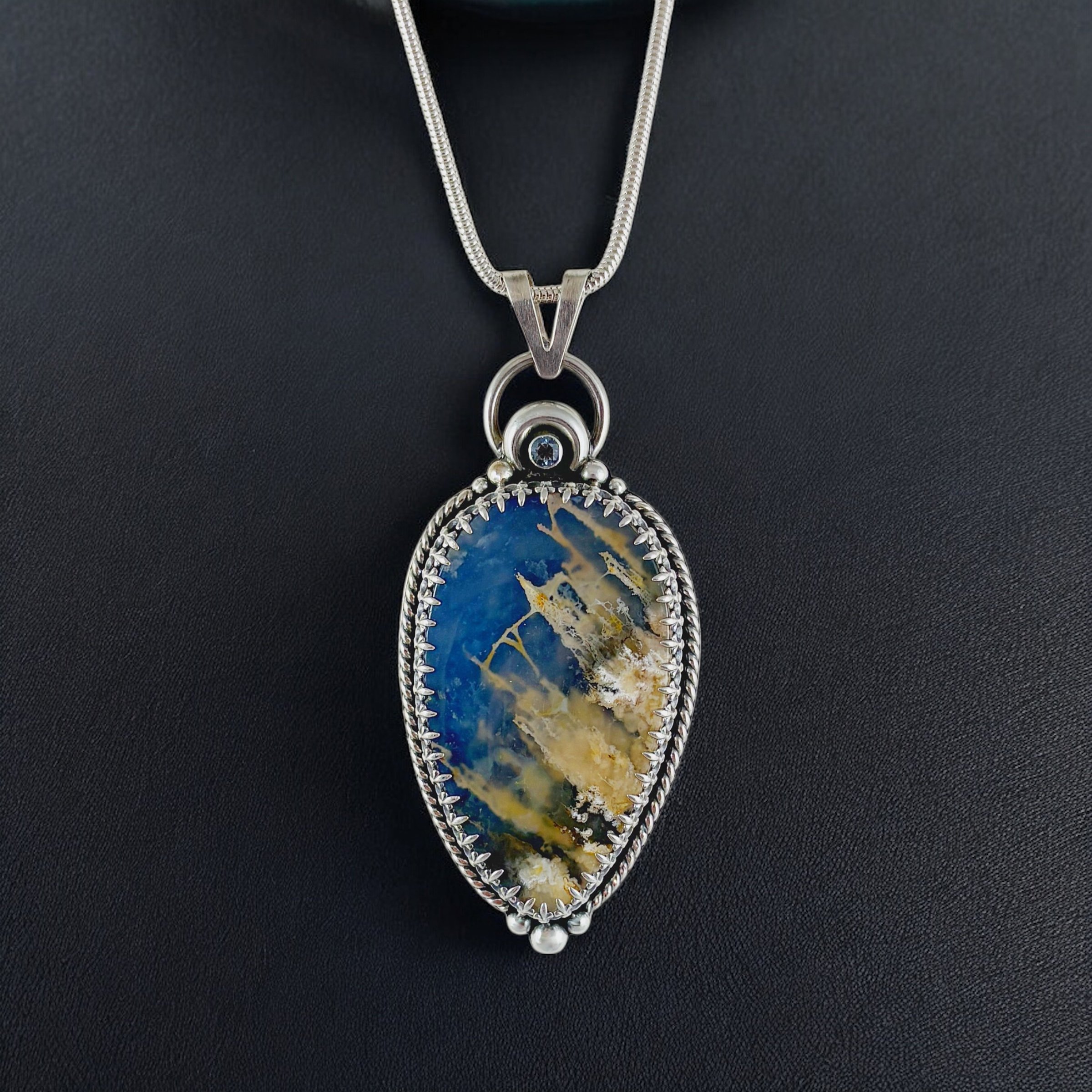 Plume agate doublet set in sterling silver with blue topaz accent.