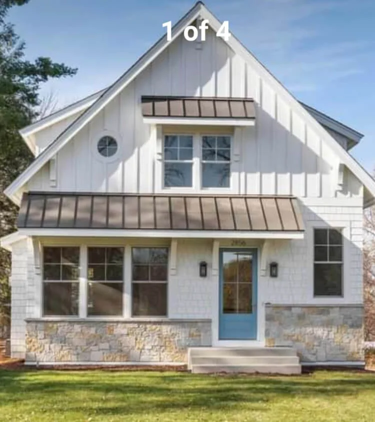 White two-story house with stone foundation, blue front door, and multiple windows, with a blue sky in the background.