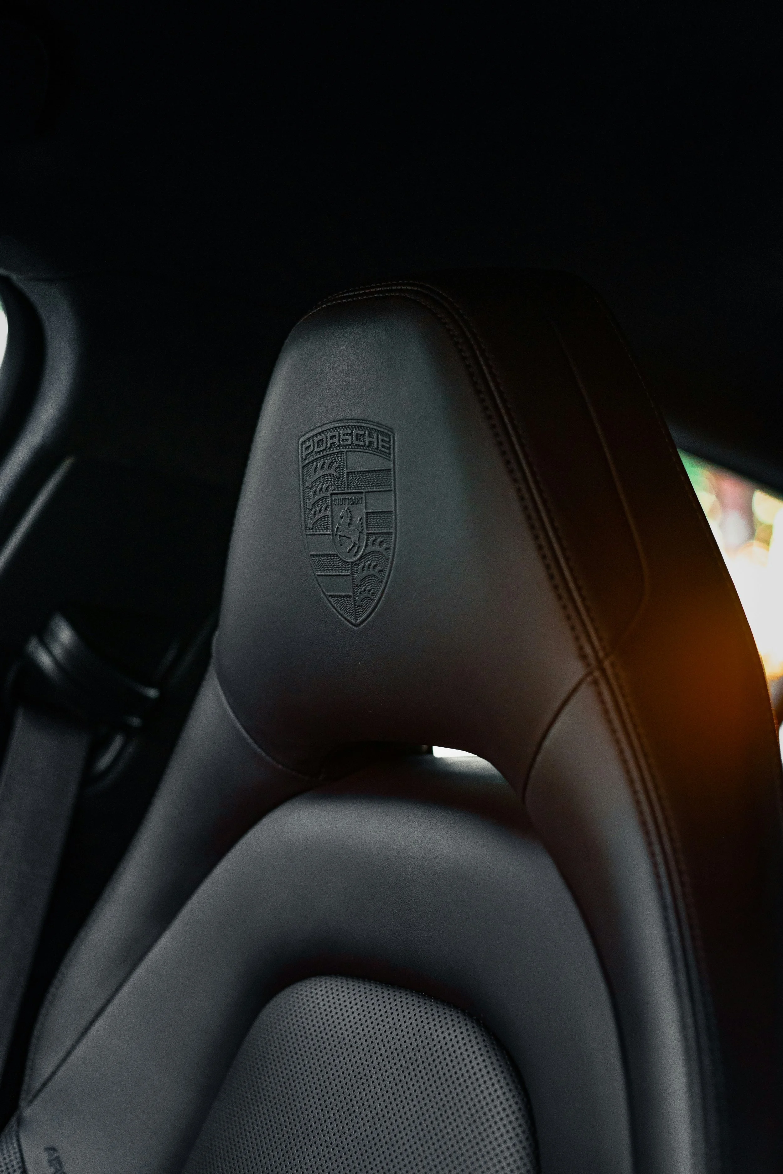 Miroir arrière d'une voiture Porsche, vue de l'intérieur, siège en cuir avec logo Porsche embossé.