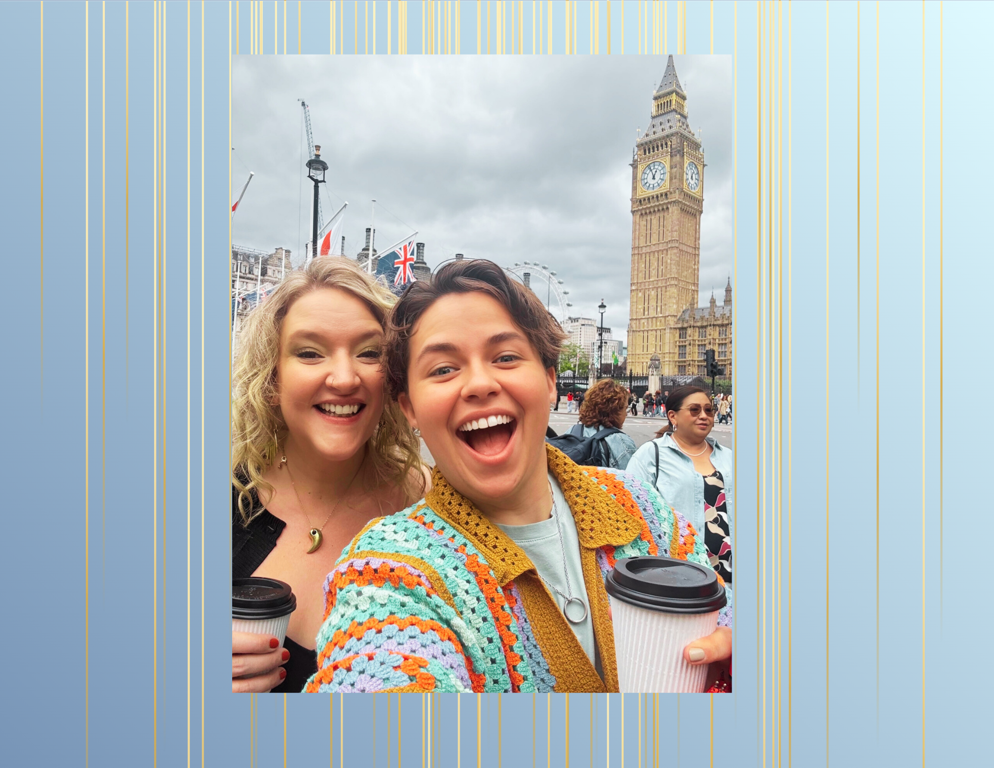 A group of friends smiling and taking a selfie in front of Big Ben in London, with the London Eye and Union Jack flags visible in the background. They are holding coffee cups and appear happy and excited.