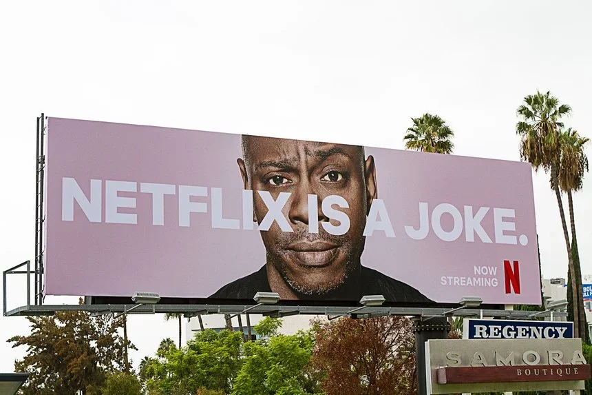 Billboard with an image of a man's face, showing a serious expression, and large text that says 'NETFLIX IS A JOKE.' with a smaller note that says 'Now streaming' and the Netflix logo.
