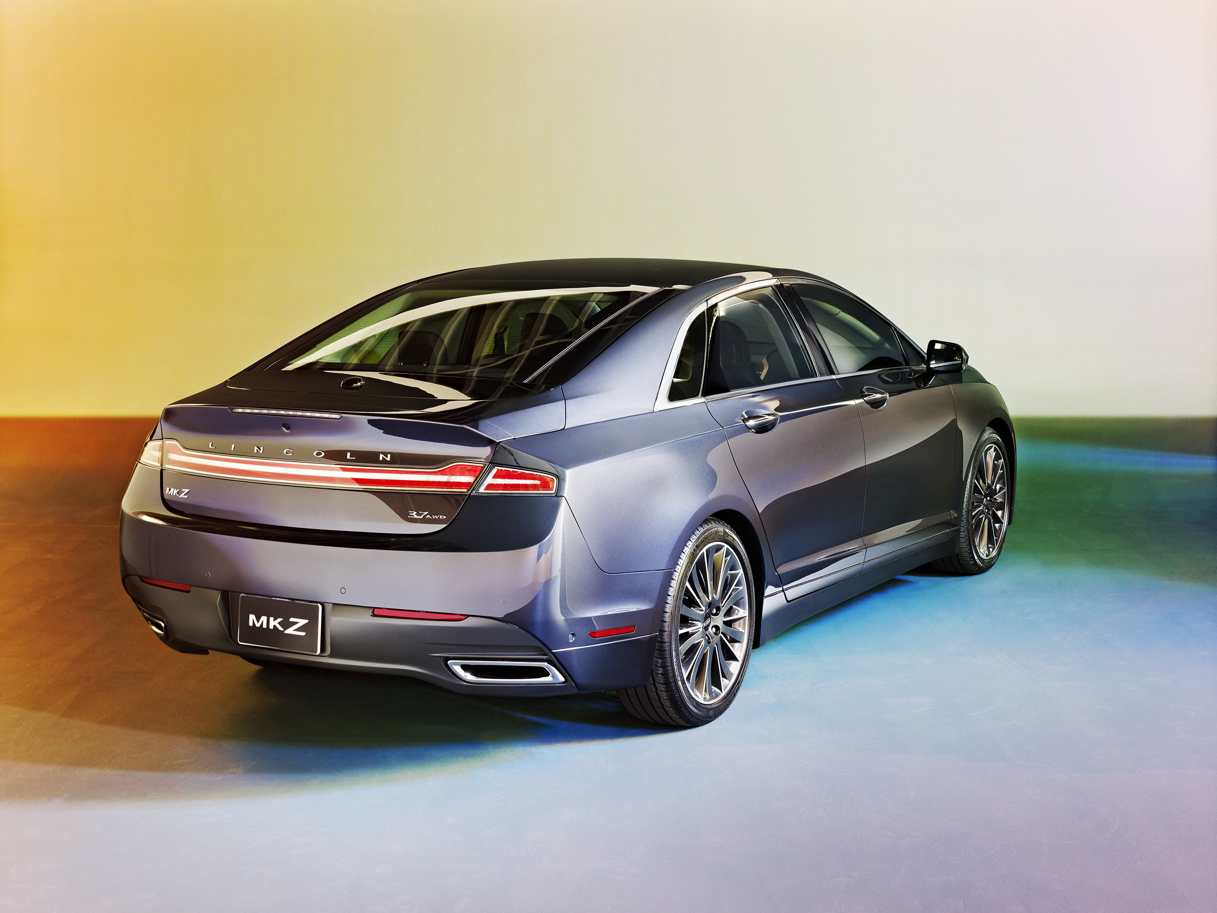 Front and side view of a sleek, dark gray Lincoln MKZ sedan with chrome accents, parked on a multicolored floor against a gradient background. Advertising. Producer. Miranda Kendrick. Adrian Gaut.