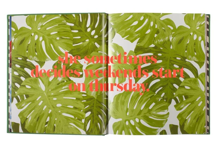 Open book with a background of large green tropical leaves and pink text that says, "she sometimes decides weekends start on Thursday."