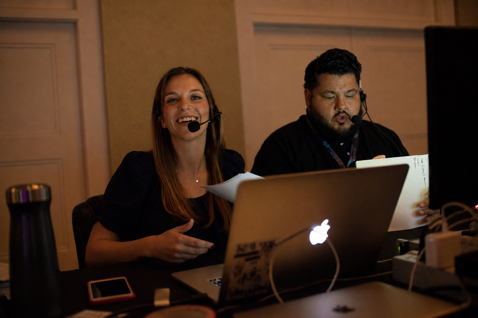 Event Planner, Camille Carlin, Founder of The CC Appetite, sitting back of house wearing a show headset working alongside the audio tech calling a large scale nonprofit gala.