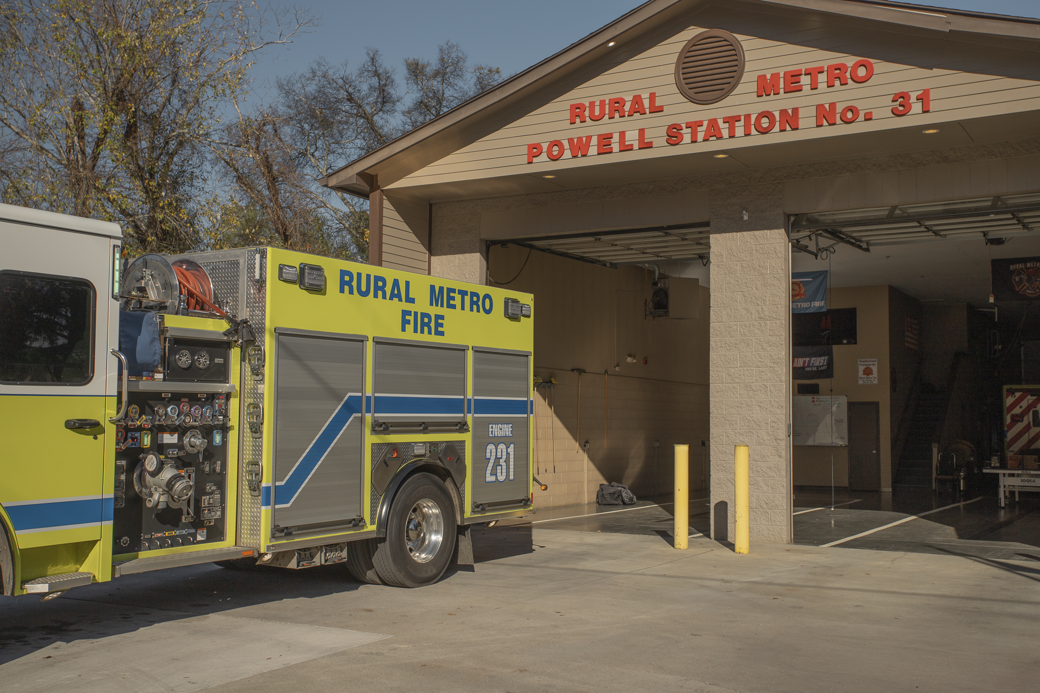 Fire truck parked outside Rural Metro Fire station Powell Station No. 31 building, which has a sign with red lettering and a circular vent on the roof overhang.