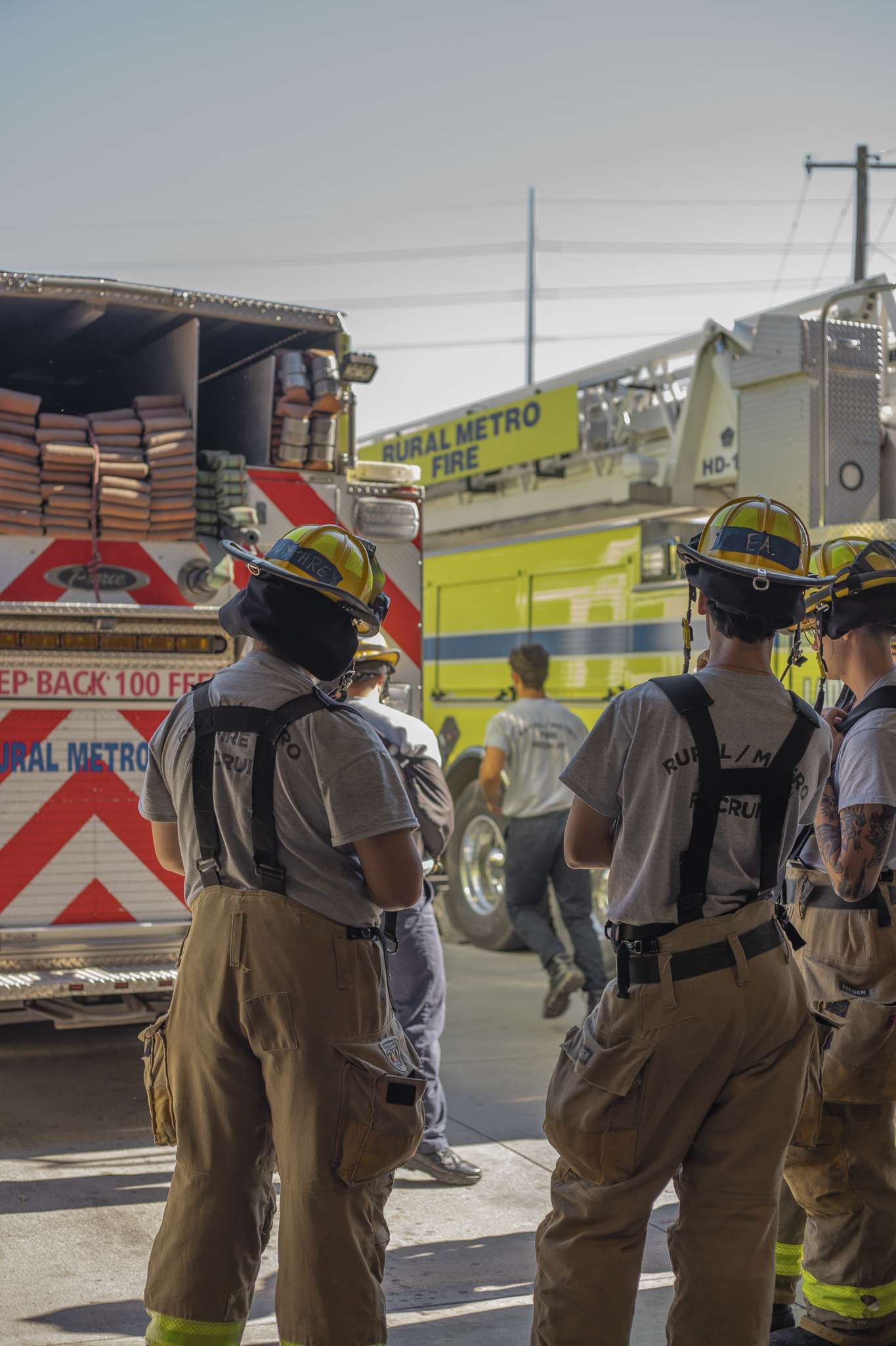 Group of firefighters in uniform standing near fire trucks during daytime.