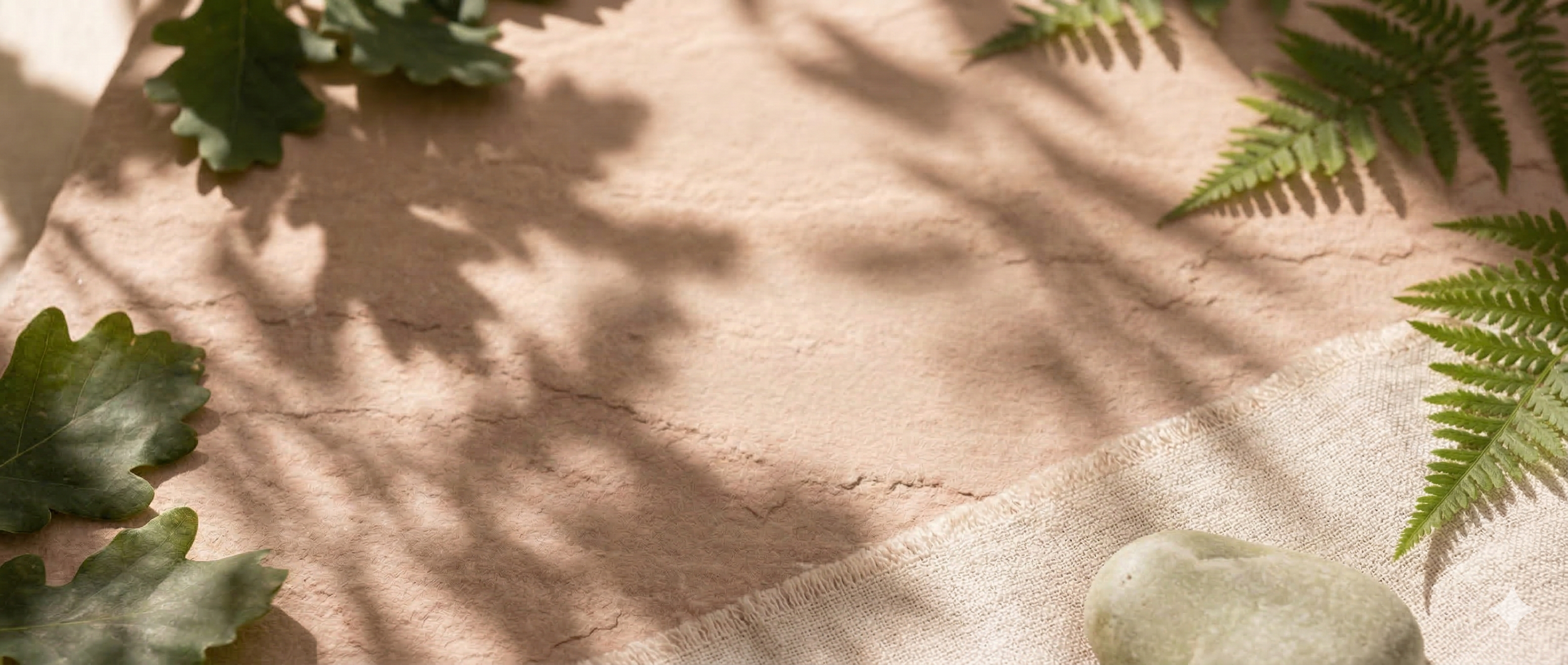 A beige textured surface with green fern leaves, oak leaves, and a light-colored stone casting shadows.