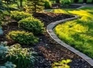 Mow Right also does mulching installation as well as lawn maintenance in Halton and Peel Regions. A landscaped garden with a curved stone border, green bushes, yellow flowers, and a grassy lawn.