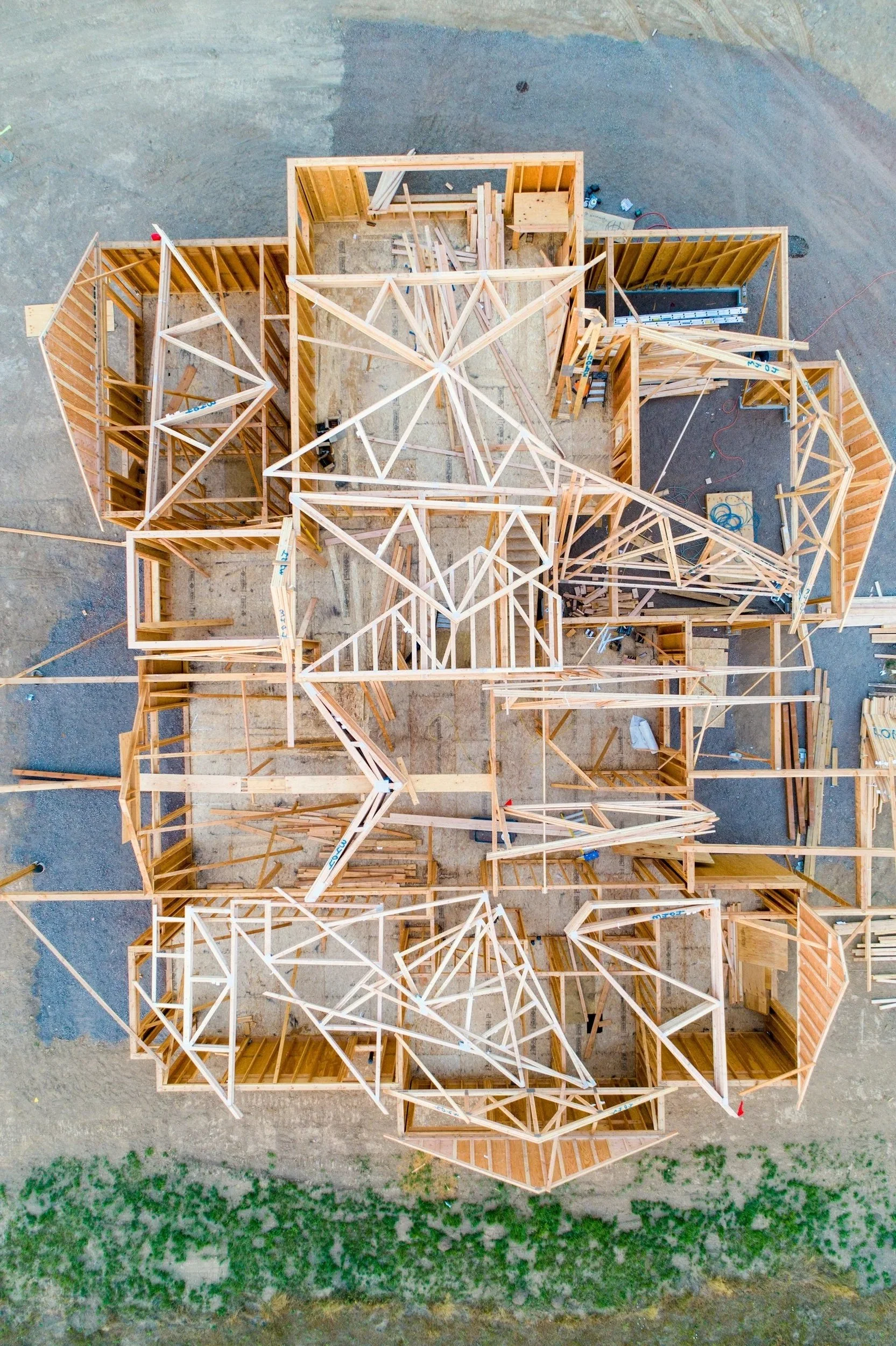 Vogelperspektive auf den Rohbau eines Hauses mit Holzwänden und Dachkonstruktion.