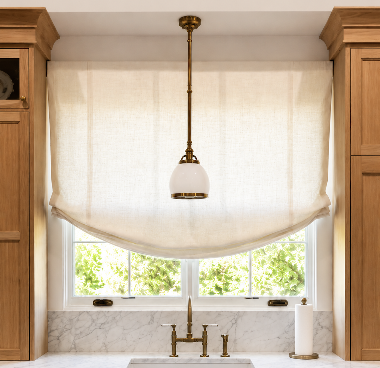 Custom relaxed Roman shade above a farmhouse sink in a warm modern kitchen