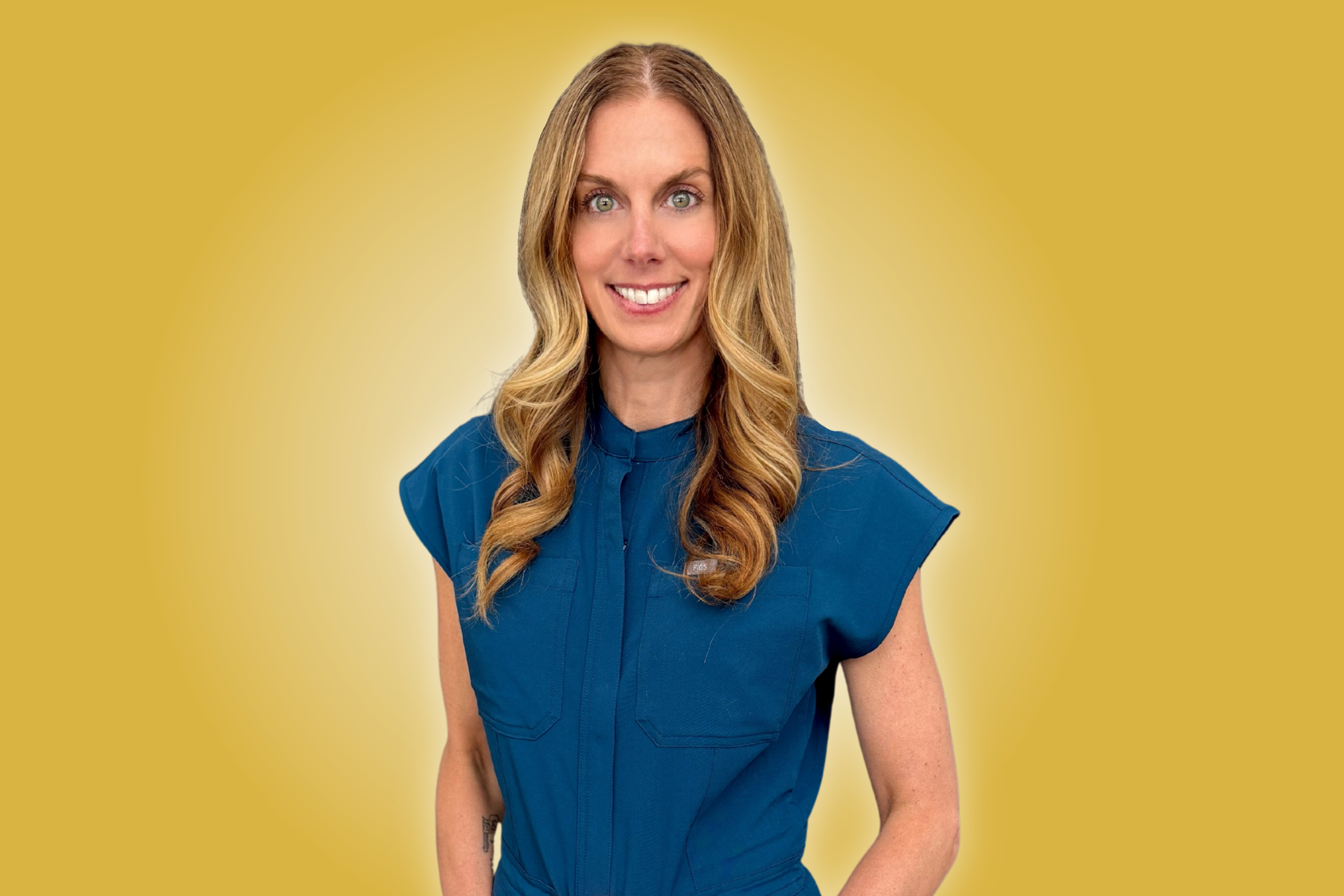 A smiling woman with long wavy blonde hair wearing a blue shirt against a yellow background.