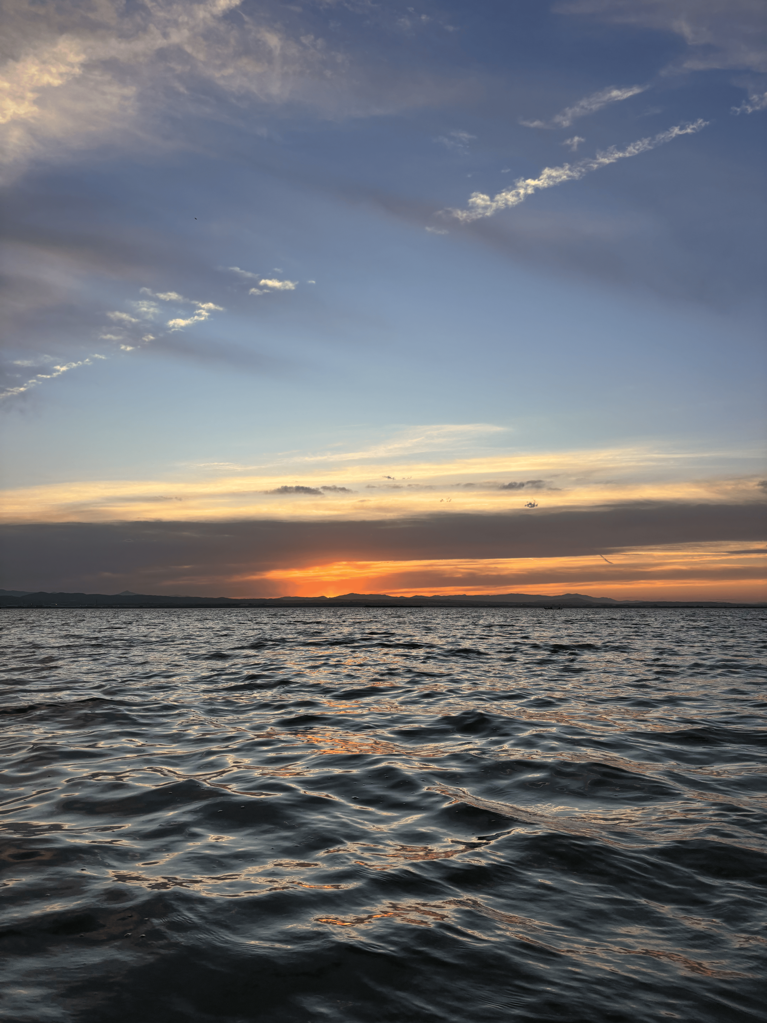 Sunset over a body of water with clouds in the sky.