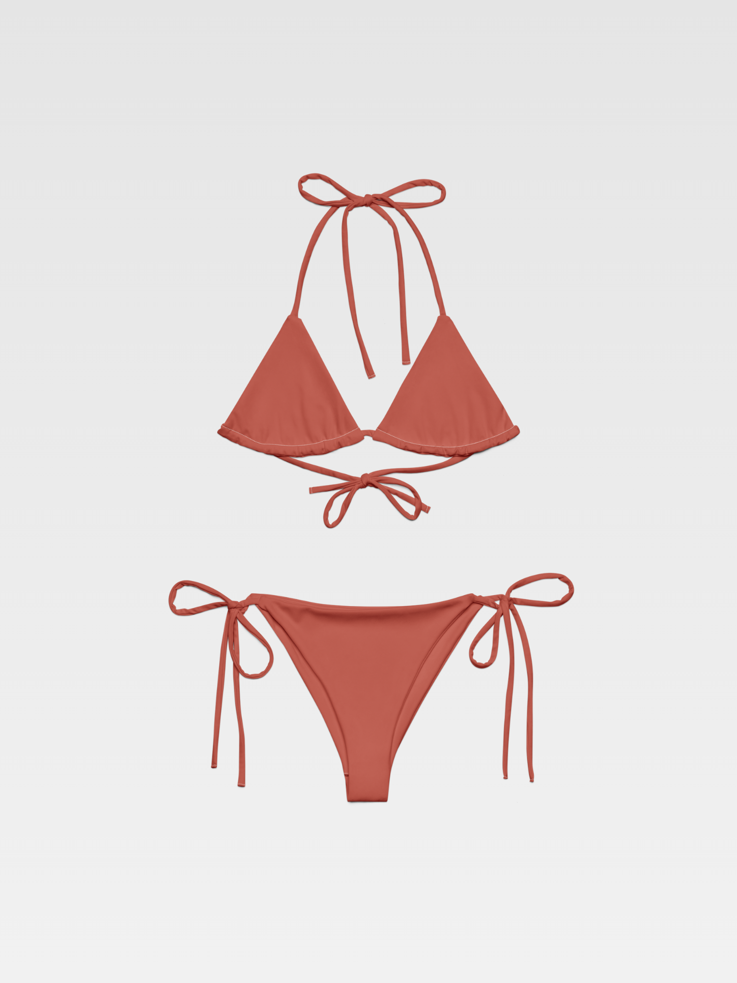 A two-piece bikini swimsuit in a muted coral color, with triangle top and string ties, displayed against a light gray background.
