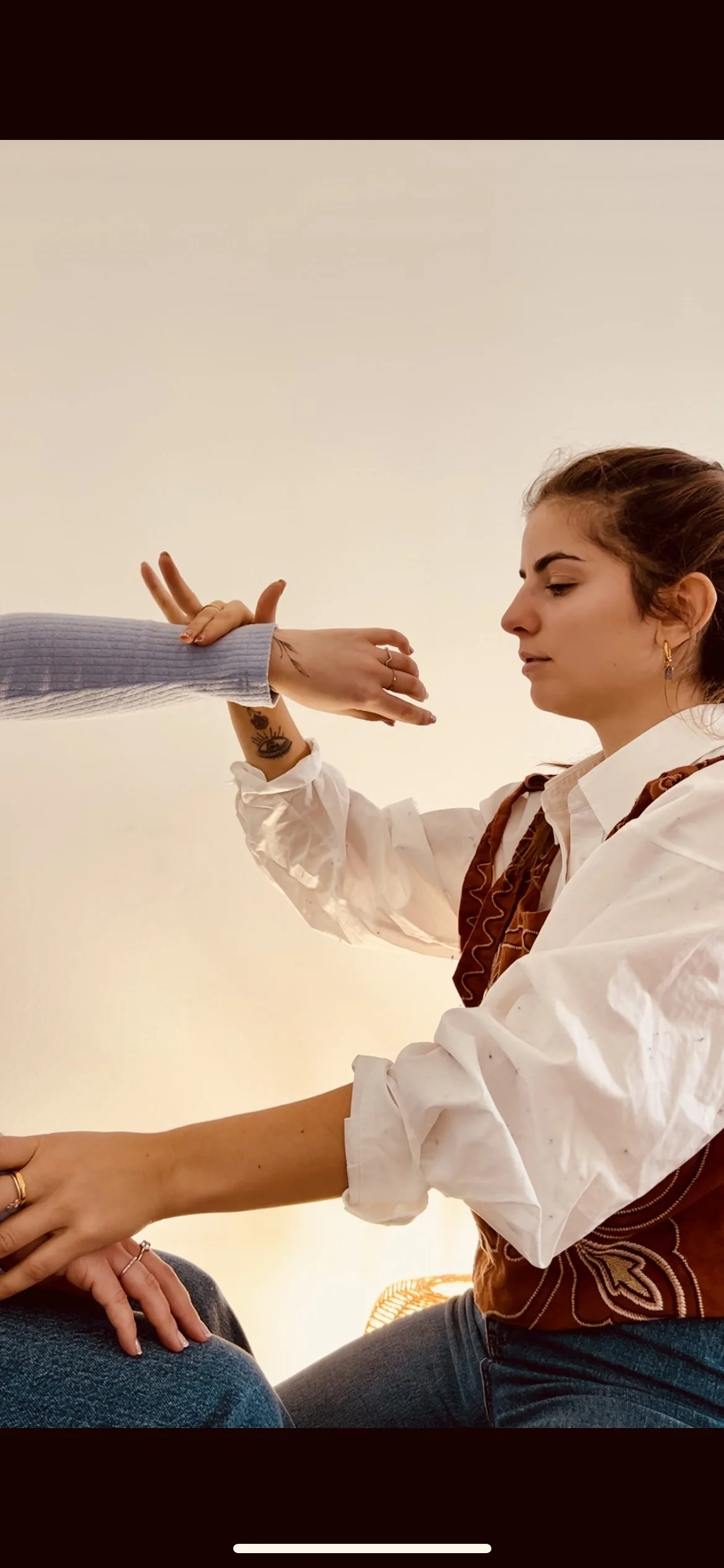 Une femme avec des tatouages prend la main d'une autre personne dans une pièce bien éclairée.