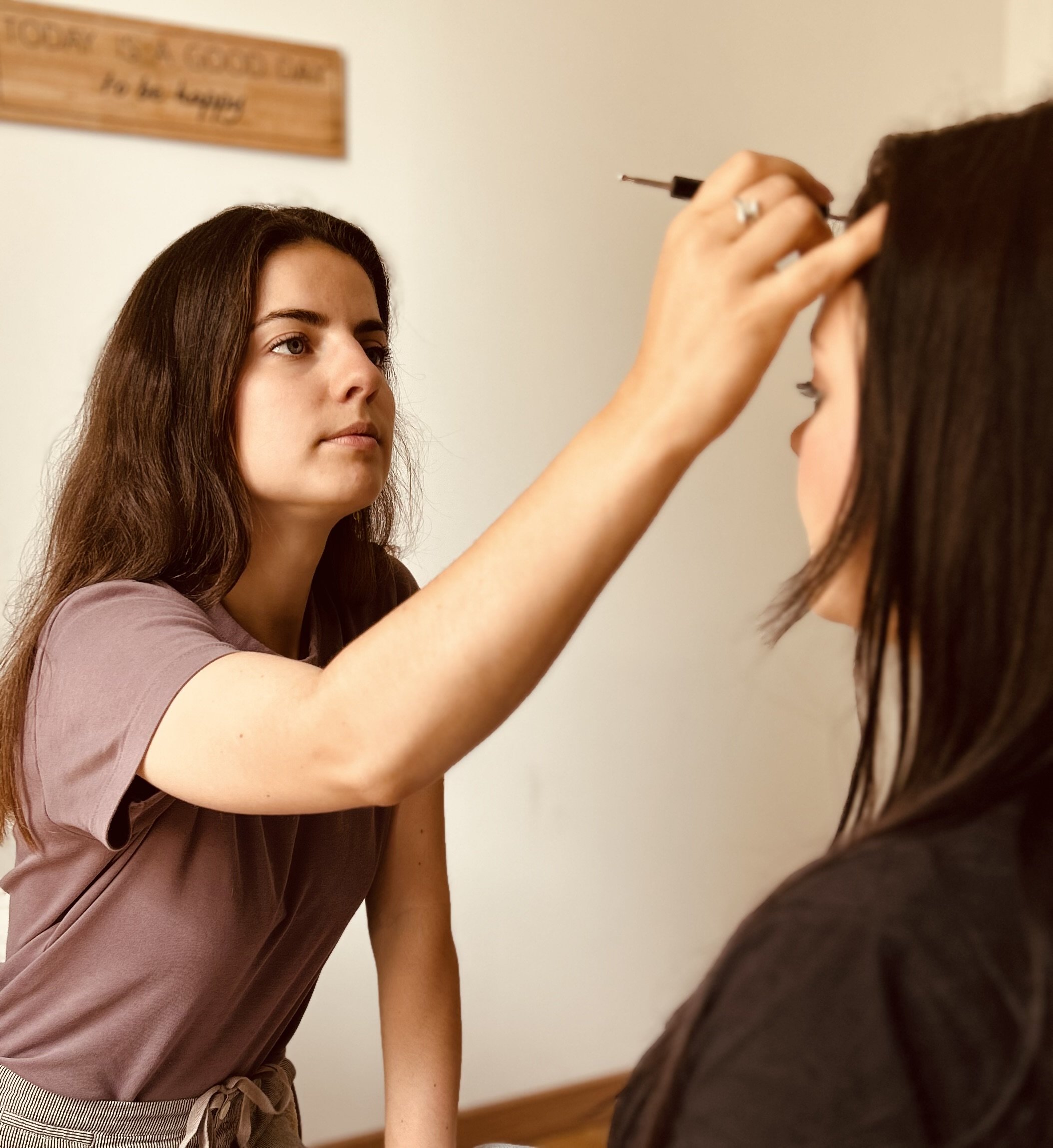 Une femme fait un maquillage artistique ou un tatouage sur le visage ou le front d'une autre femme dans un intérieur