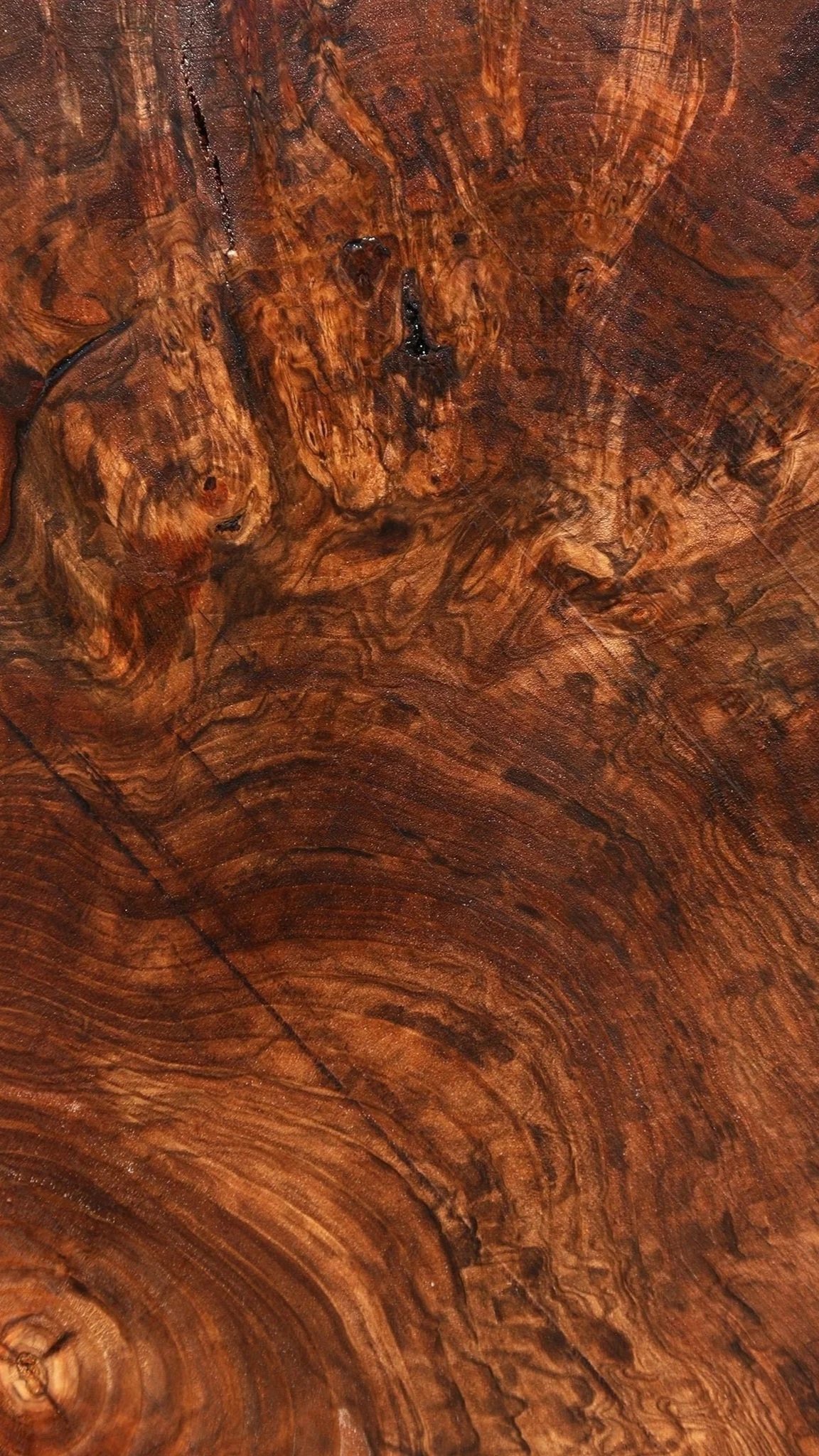 Close-up of richly grained, dark brown wood surface with natural patterns and knots.