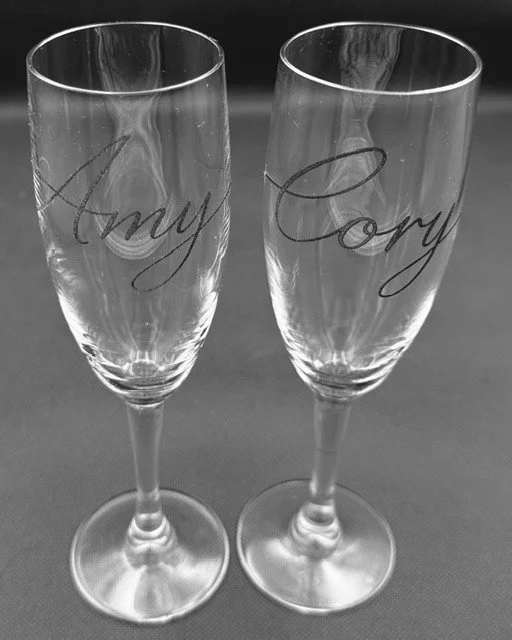 Two champagne flutes with the words "Anny" and "Cory" written on them in cursive.