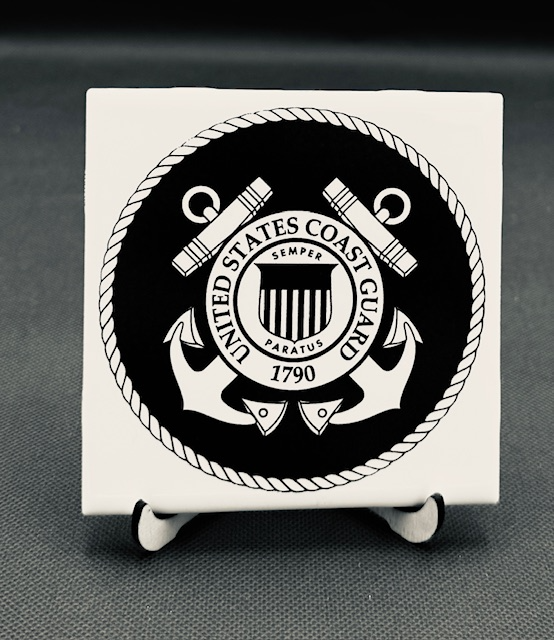 White plaque engraved  with U.S. Coast Guard badge with crossed torches, anchors, and the Coast Guard shield, featuring the words 'United States Coast Guard' and the year 1790.