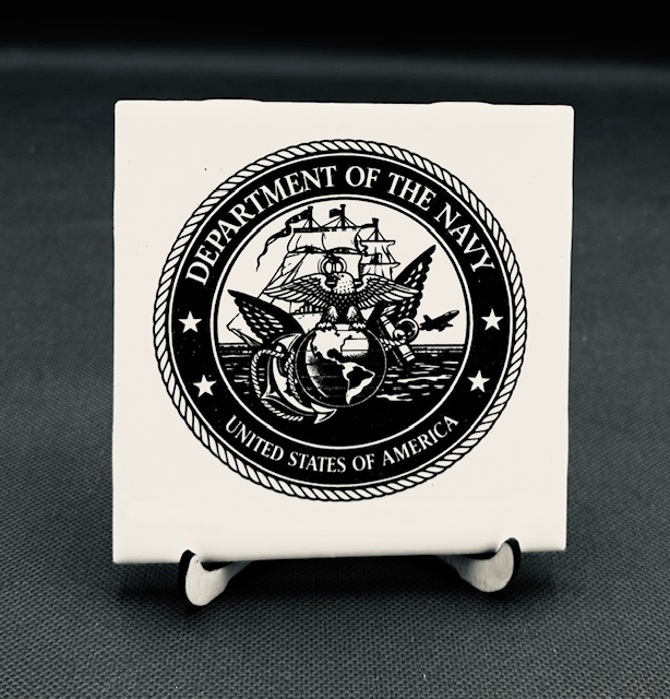 White plaque engraved with the Department of the Navy seal in black and white.