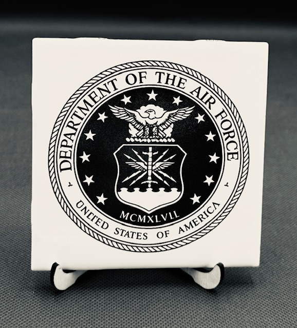White plaque engraved  with the Seal of the United States Air Force Department featuring an eagle, a shield with three lightning bolts, and the Roman numerals MCMLXLVII.