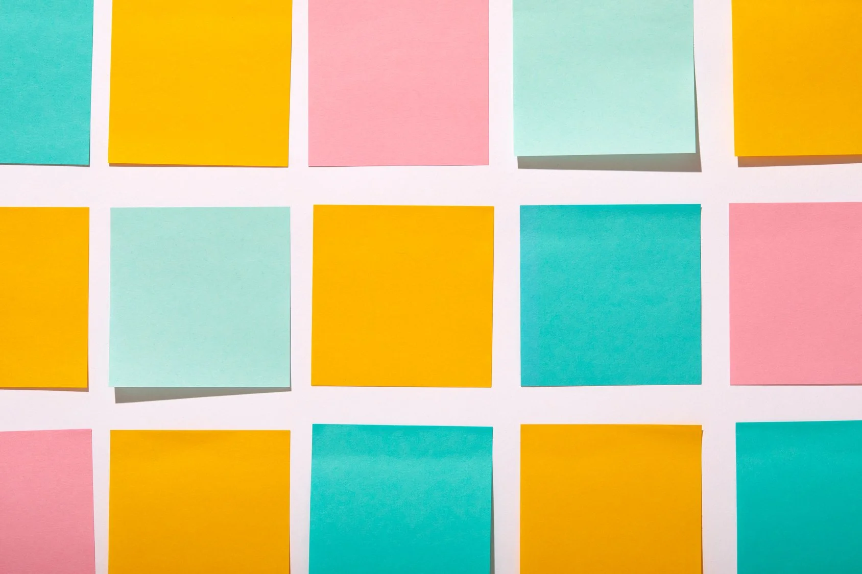 Colorful sticky notes arranged in a grid on a white background, featuring pink, yellow, light blue, and teal notes.