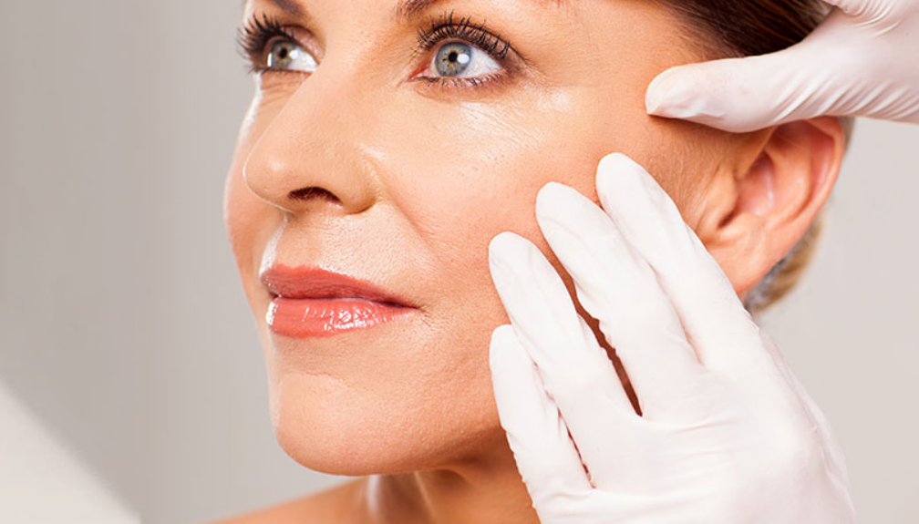 A woman receiving a cosmetic facial procedure, with a healthcare professional wearing gloves.