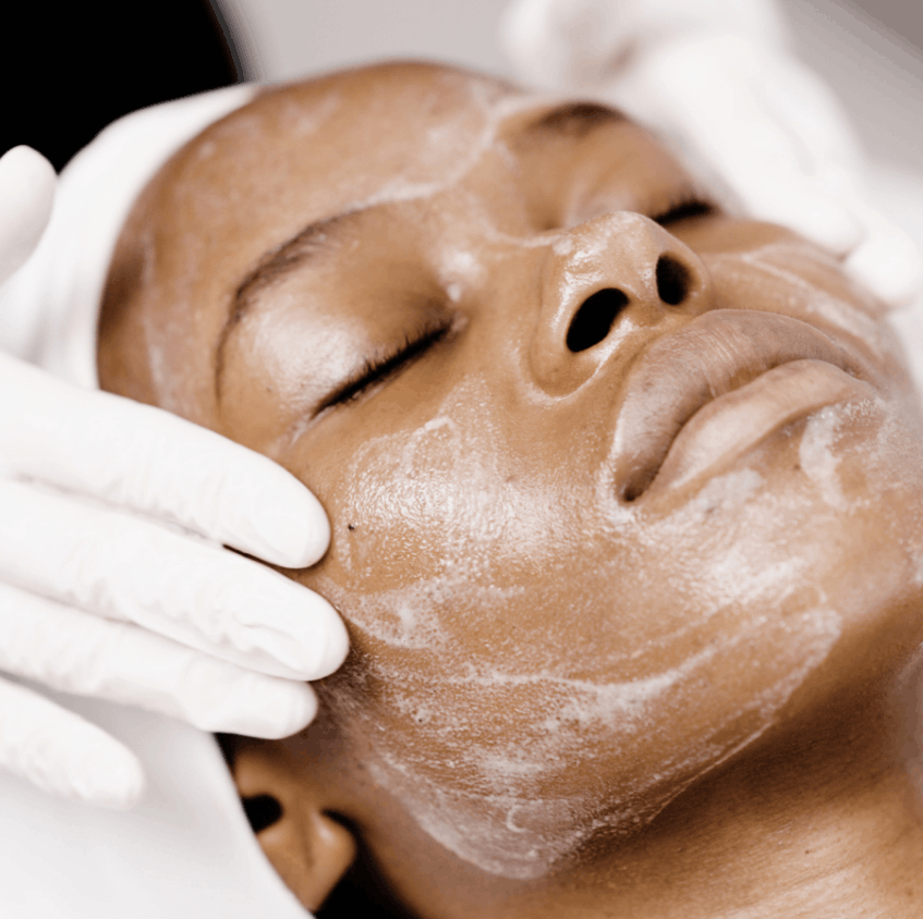 A woman receiving a professional facial while a skincare specialist applies hydrating serums, antioxidants, and collagen-boosting ingredients to nourish the skin, smooth fine lines, and reveal a brighter, more youthful-looking complexion