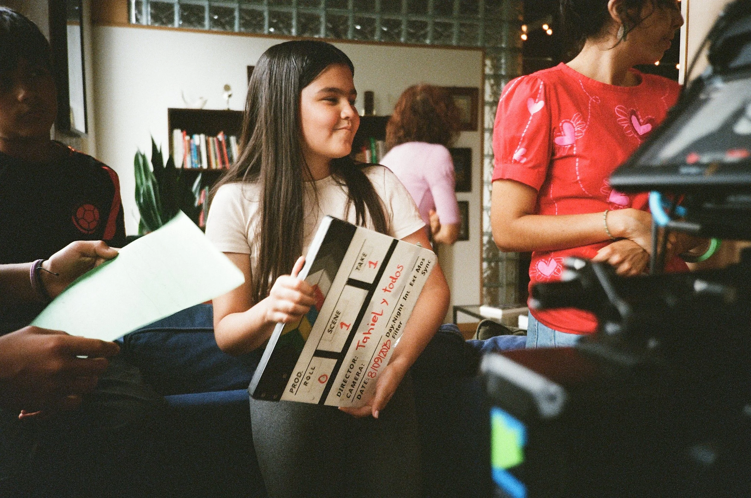 Young woman holding a clapperboard on a film set or production location.
